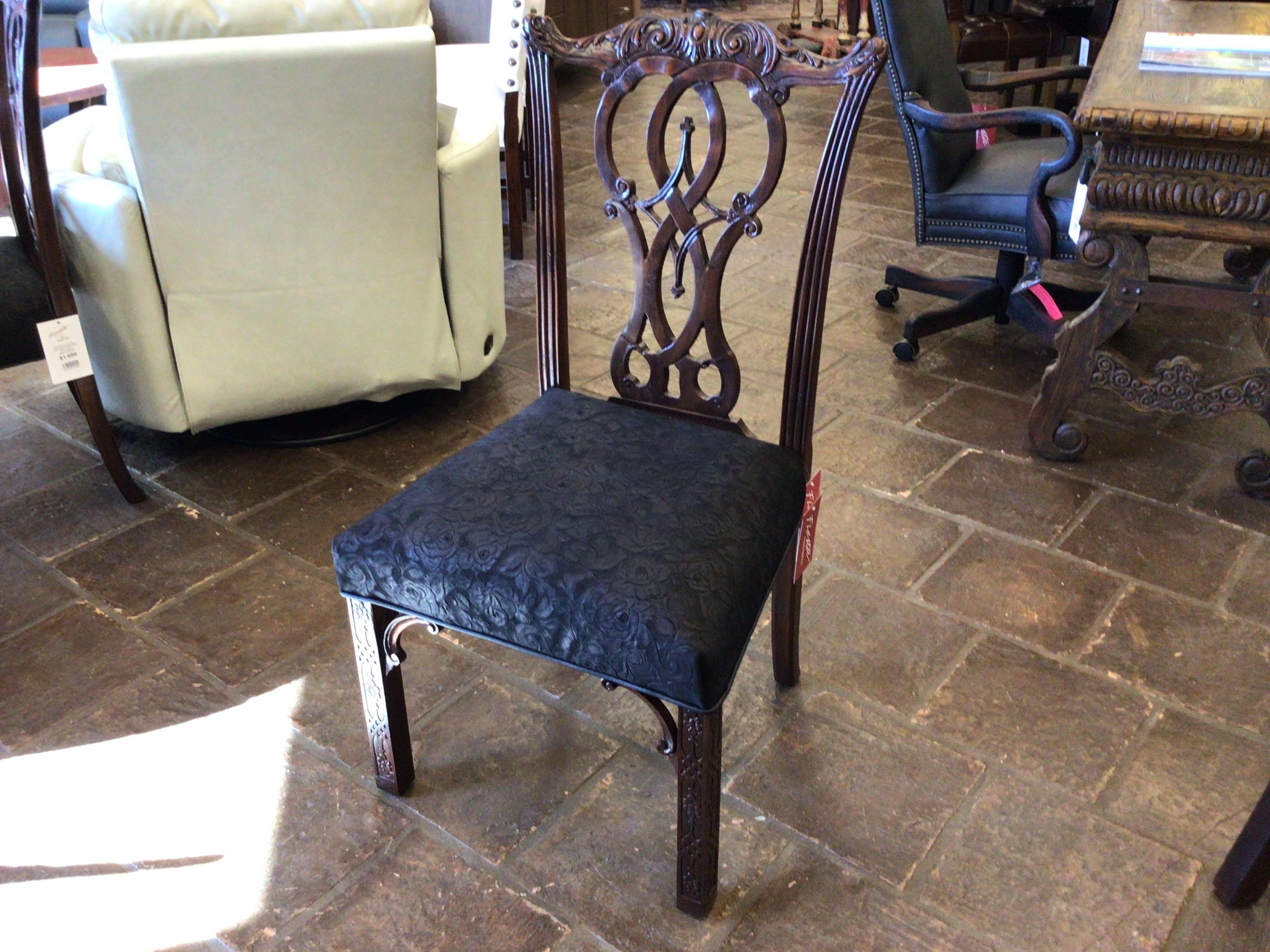Chair with black cushioned seat on a stone floor in a showroom setting