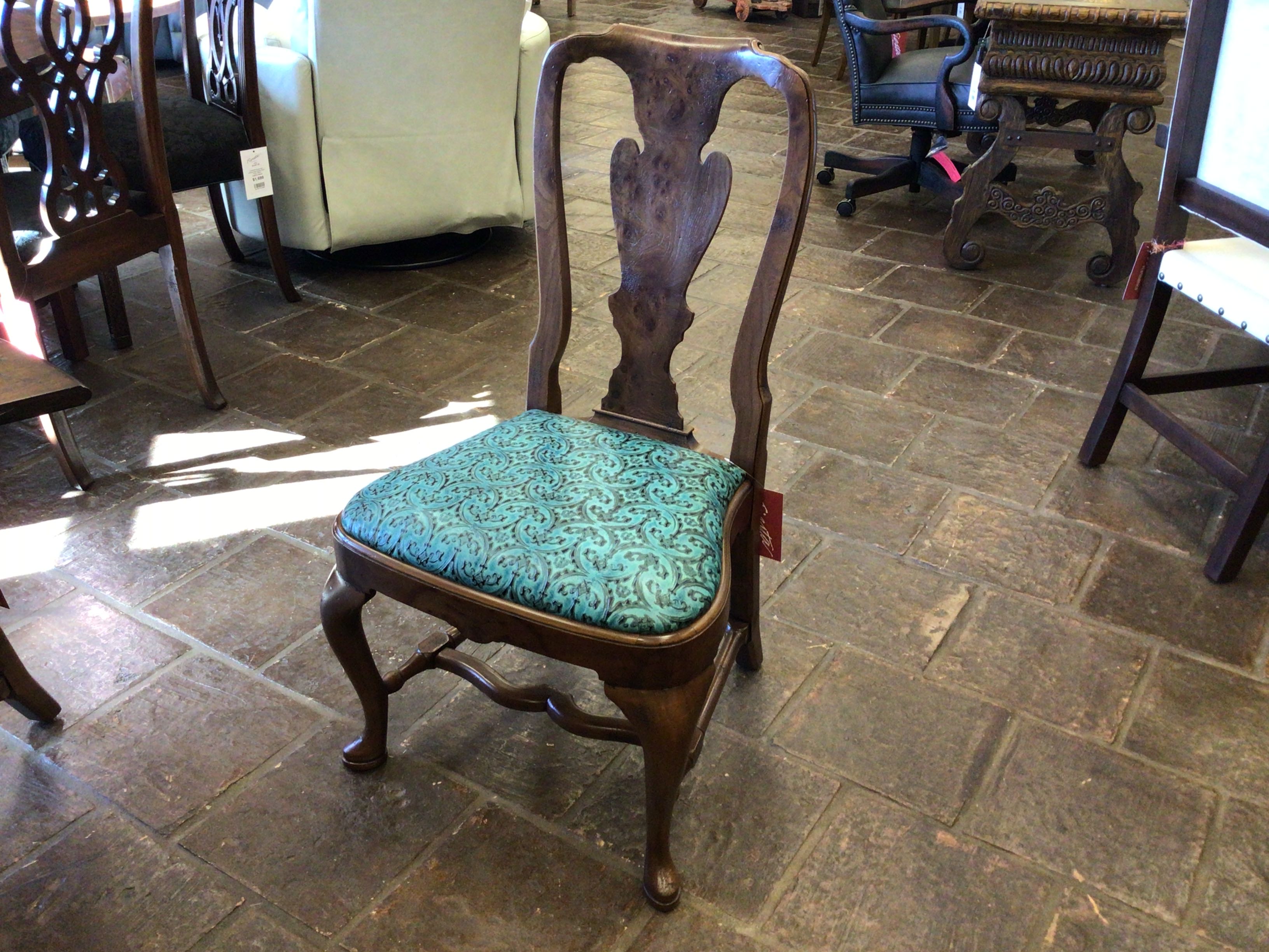 Wooden chair with a turquoise cushion on a stone floor