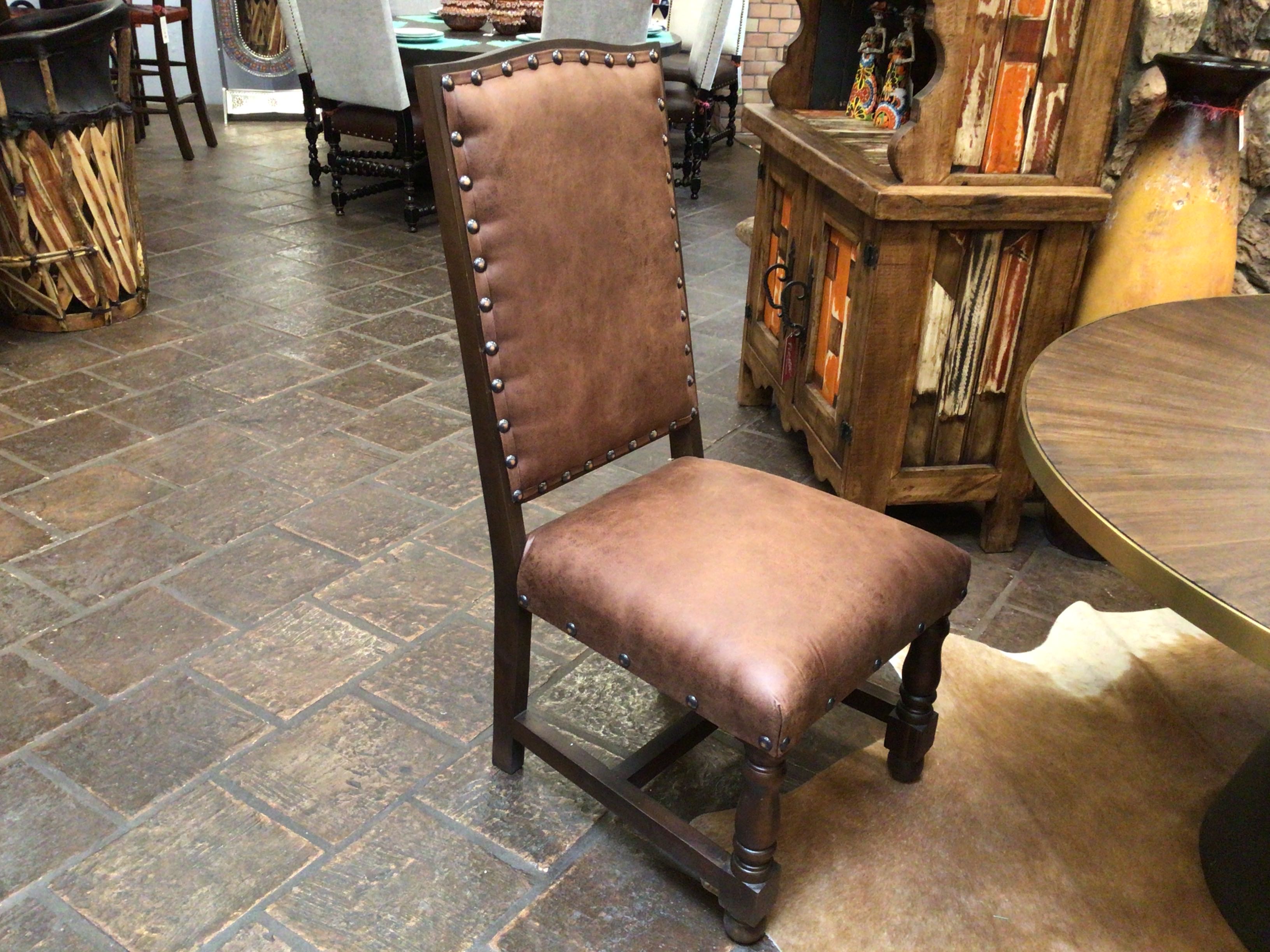 Brown leather chair with wooden frame on a stone floor