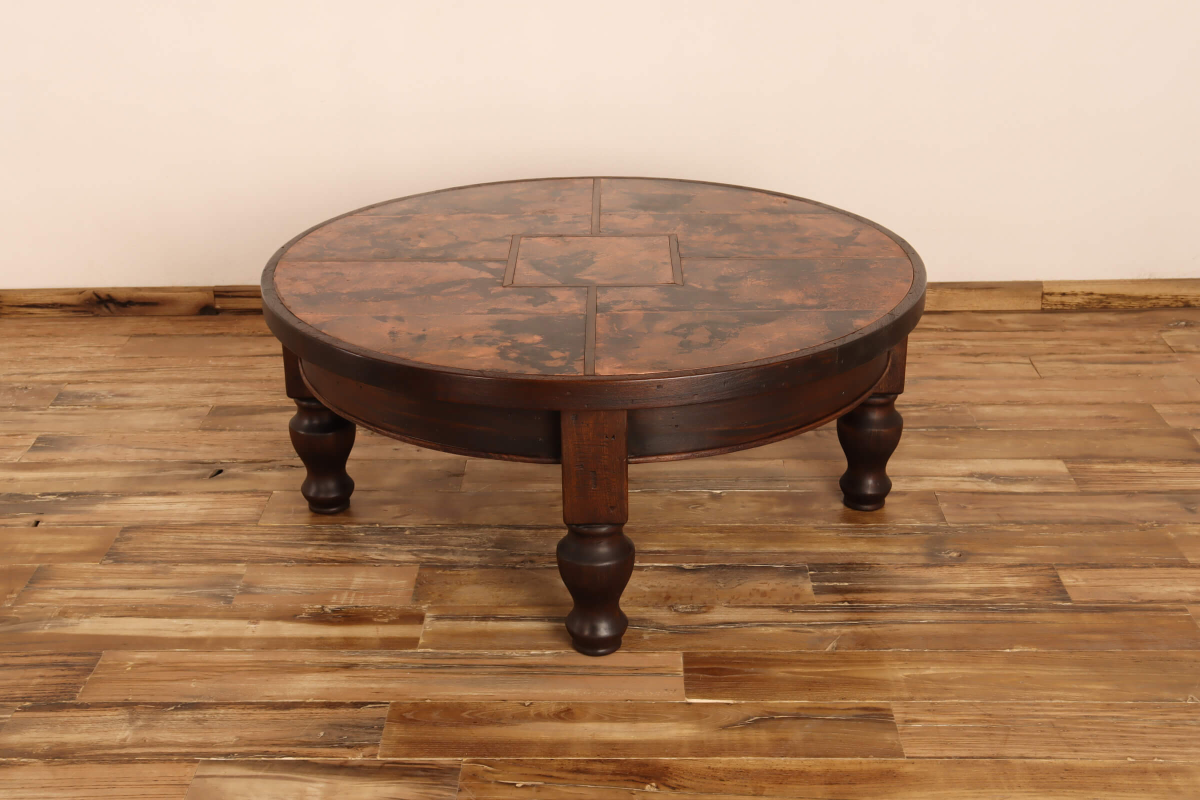 Round wooden table with a checkered pattern on a wooden floor.