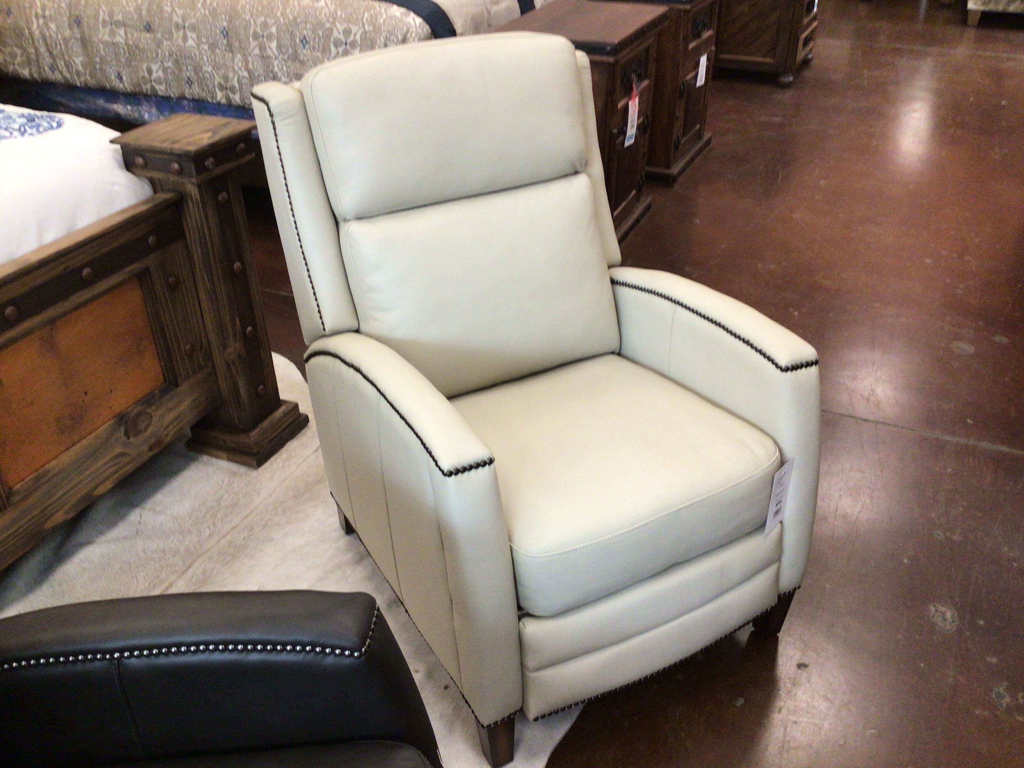 Beige recliner chair with black trim in a furniture store setting