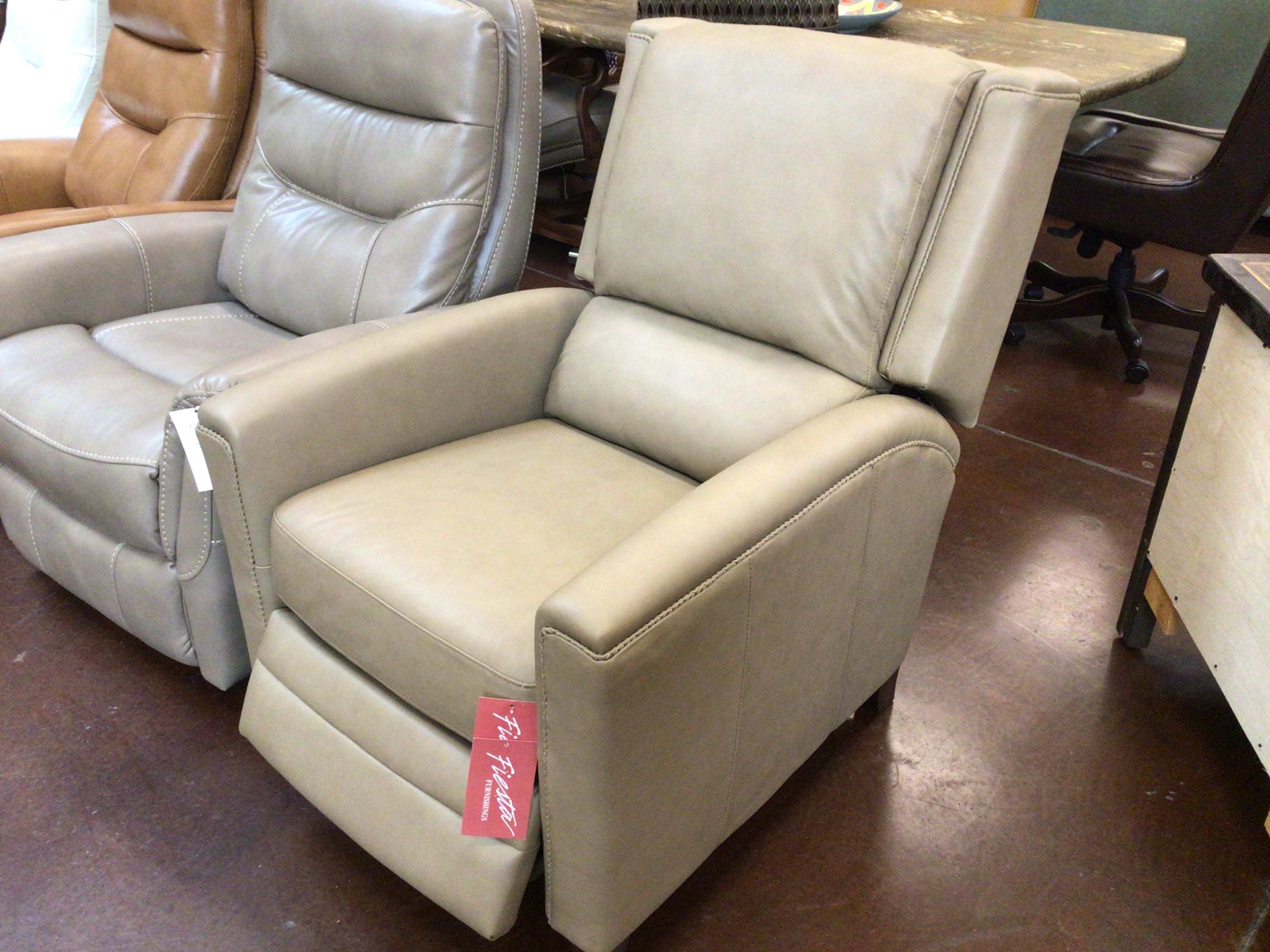 Beige recliner chairs in a showroom setting with a visible tag.