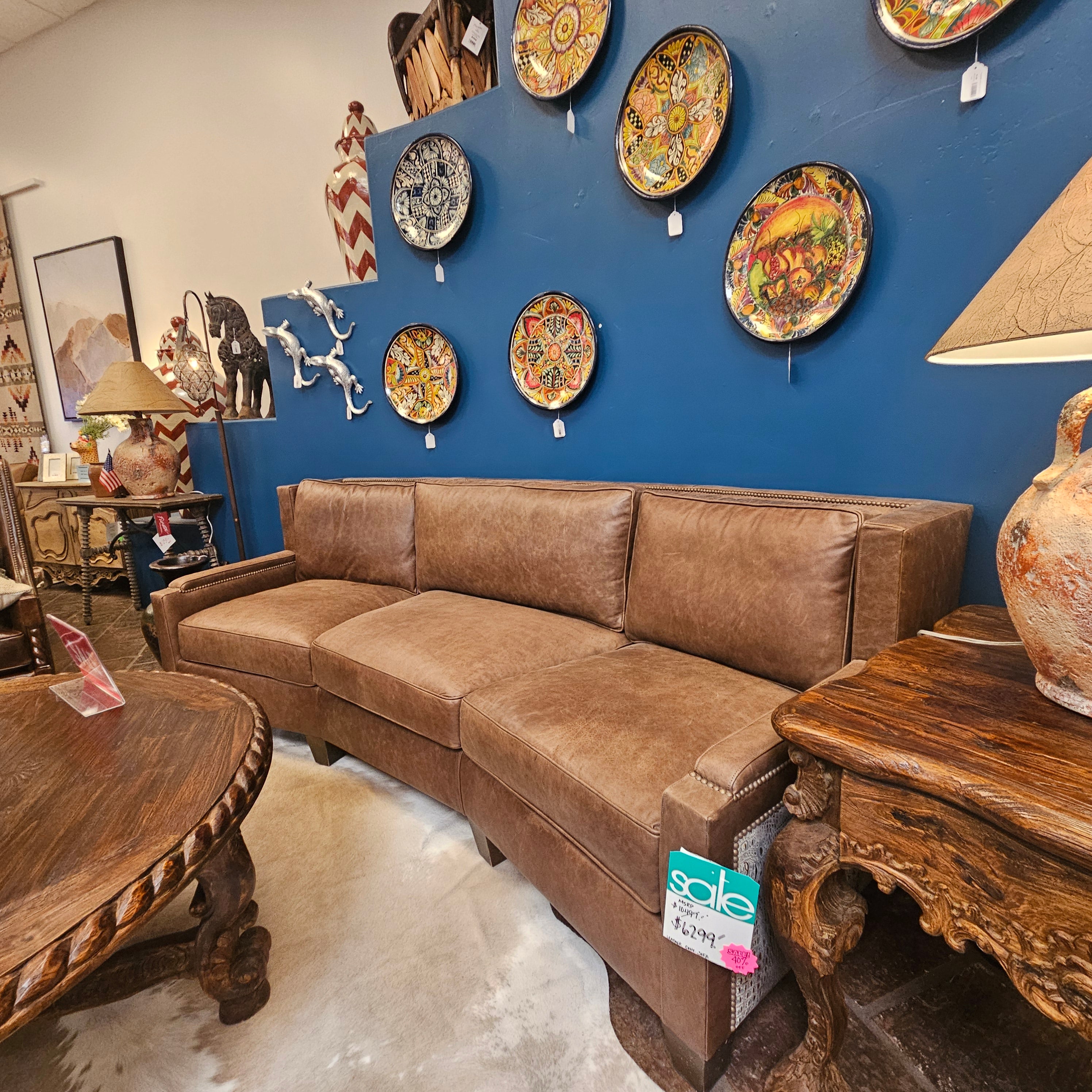 Brown sectional sofa in a room with decorative plates on the wall and wooden furniture.