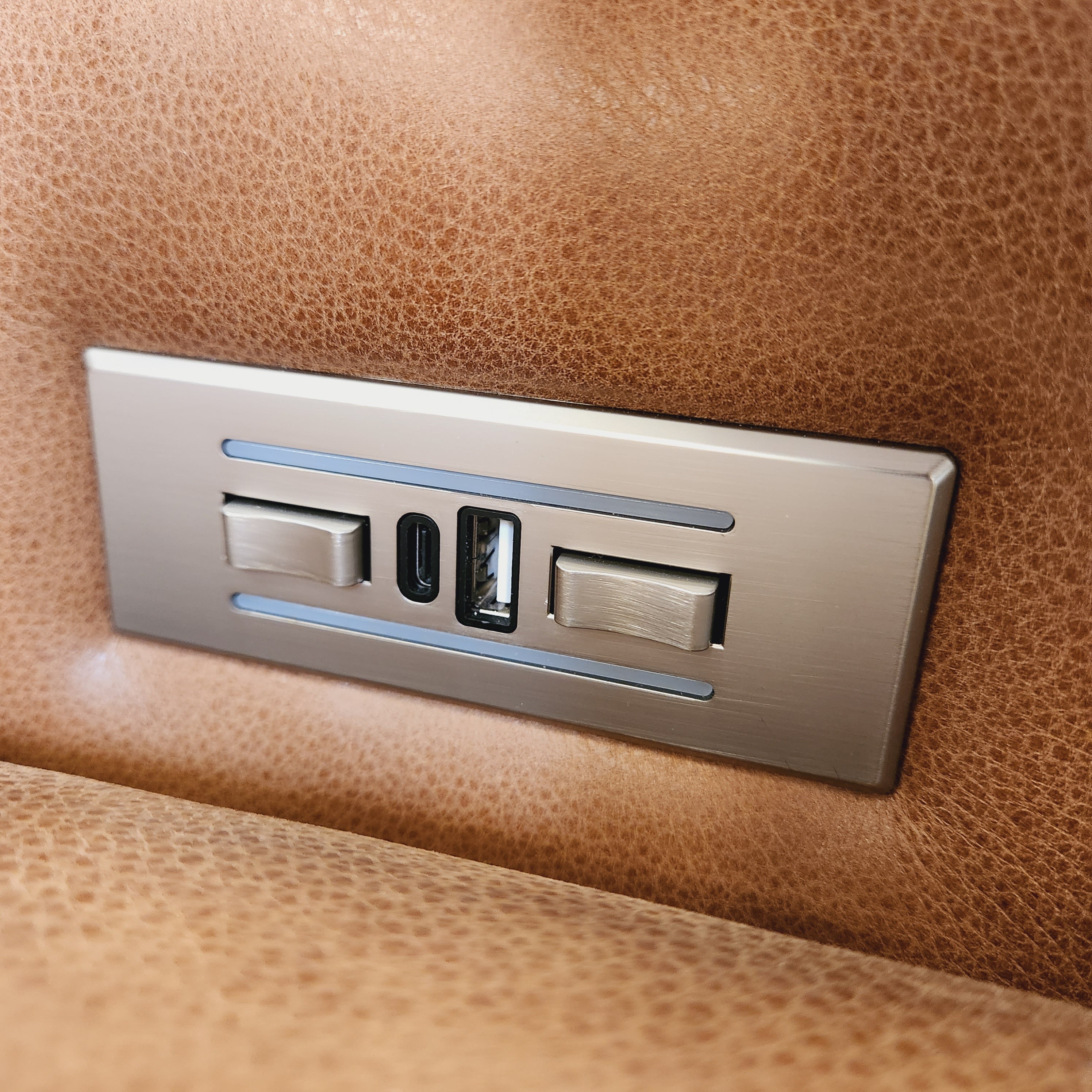 Metallic light switch panel on a brown leather surface