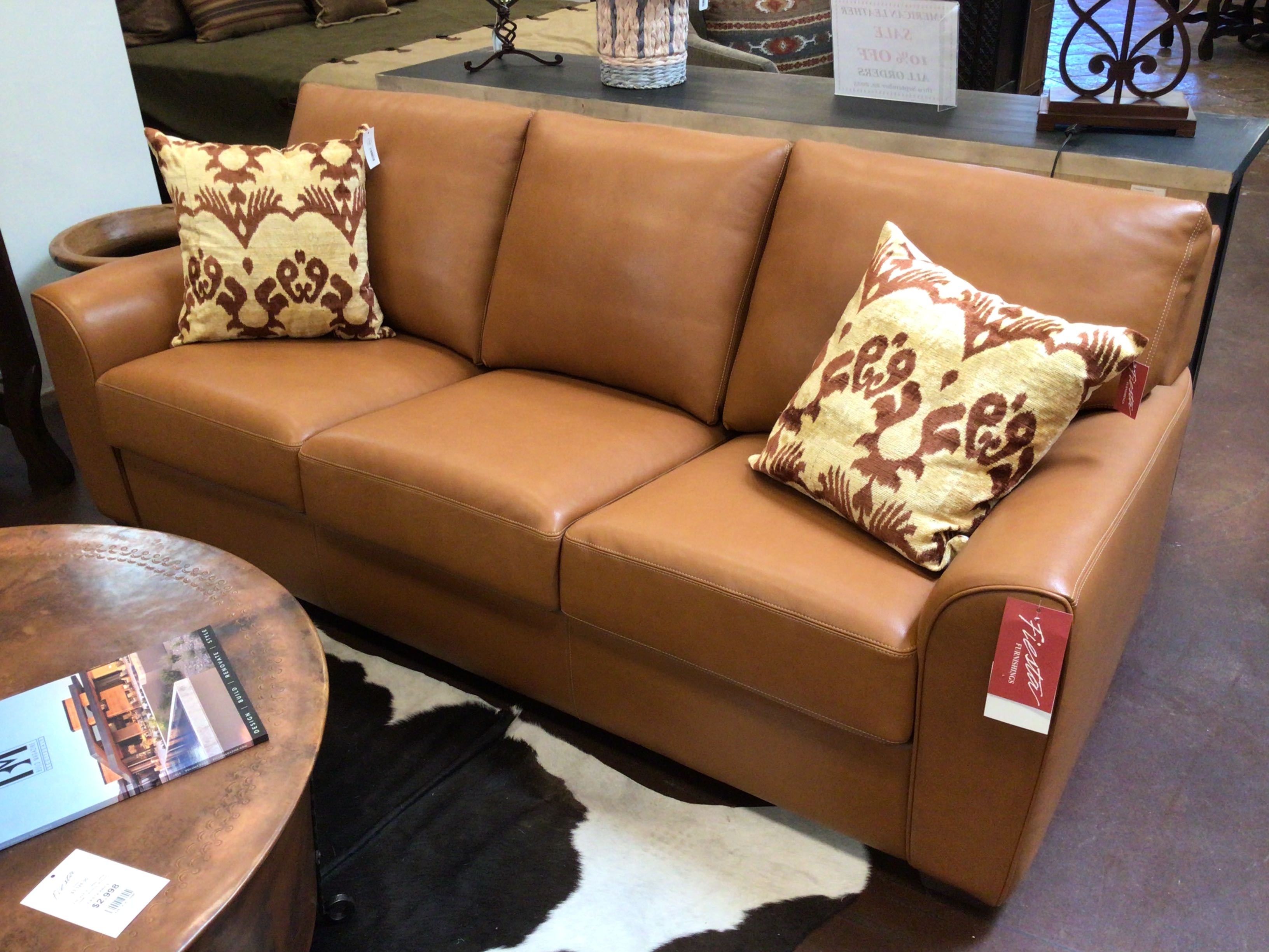 Brown leather sofa with patterned pillows in a showroom setting