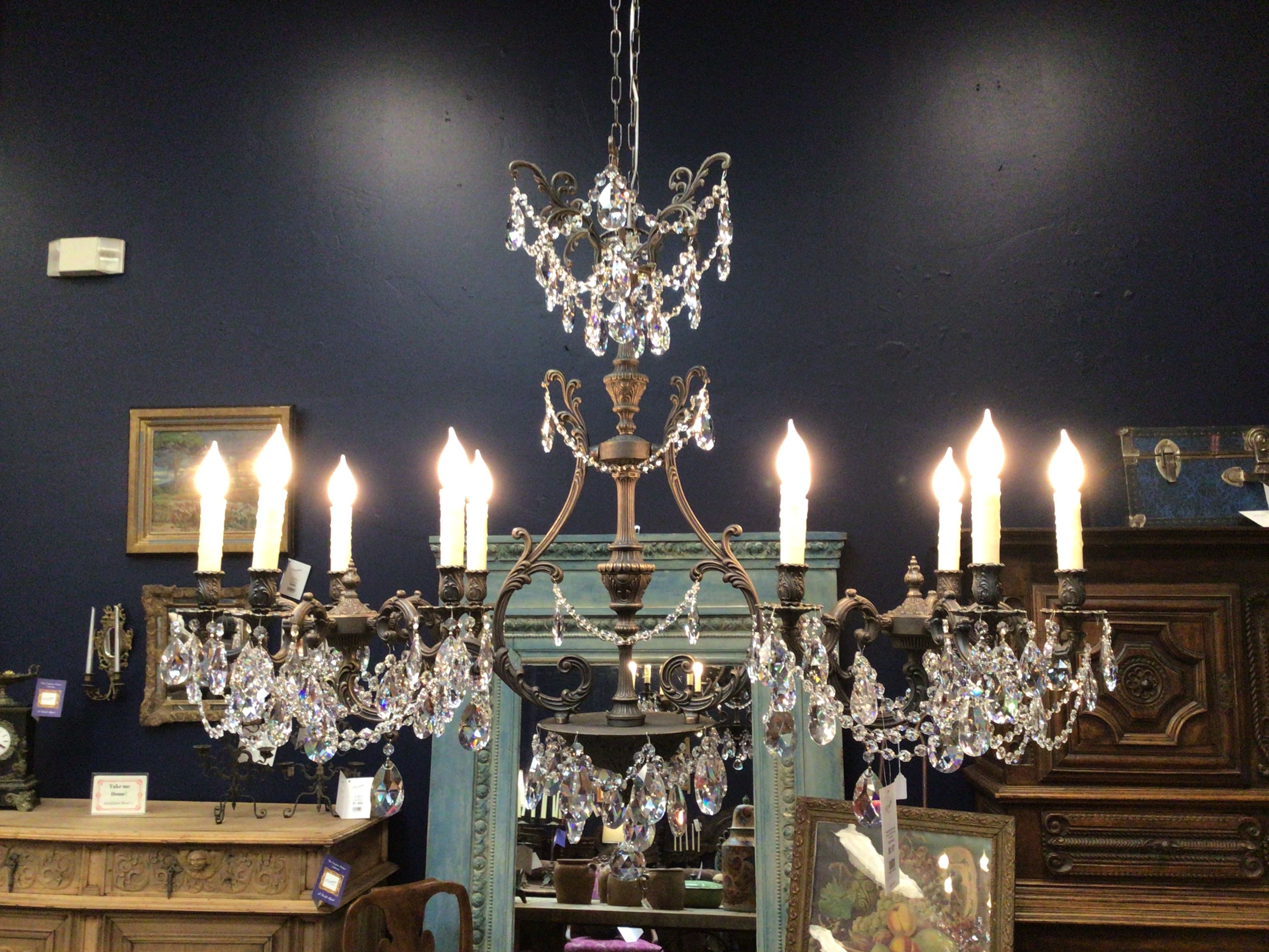 Decorative chandelier with candles in a room with dark walls and wooden furniture.