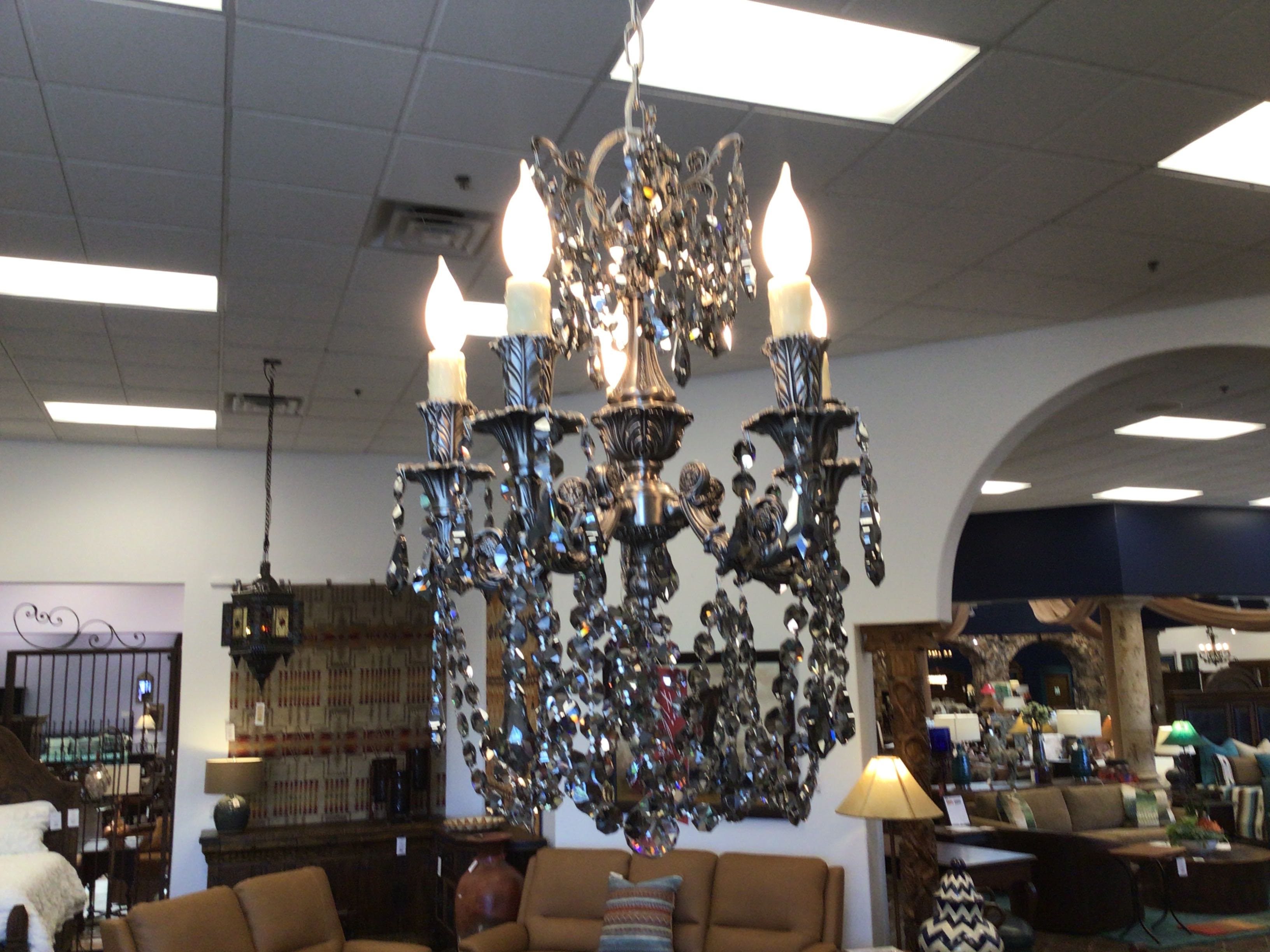 Decorative chandelier hanging in a room with furniture and lighting fixtures.