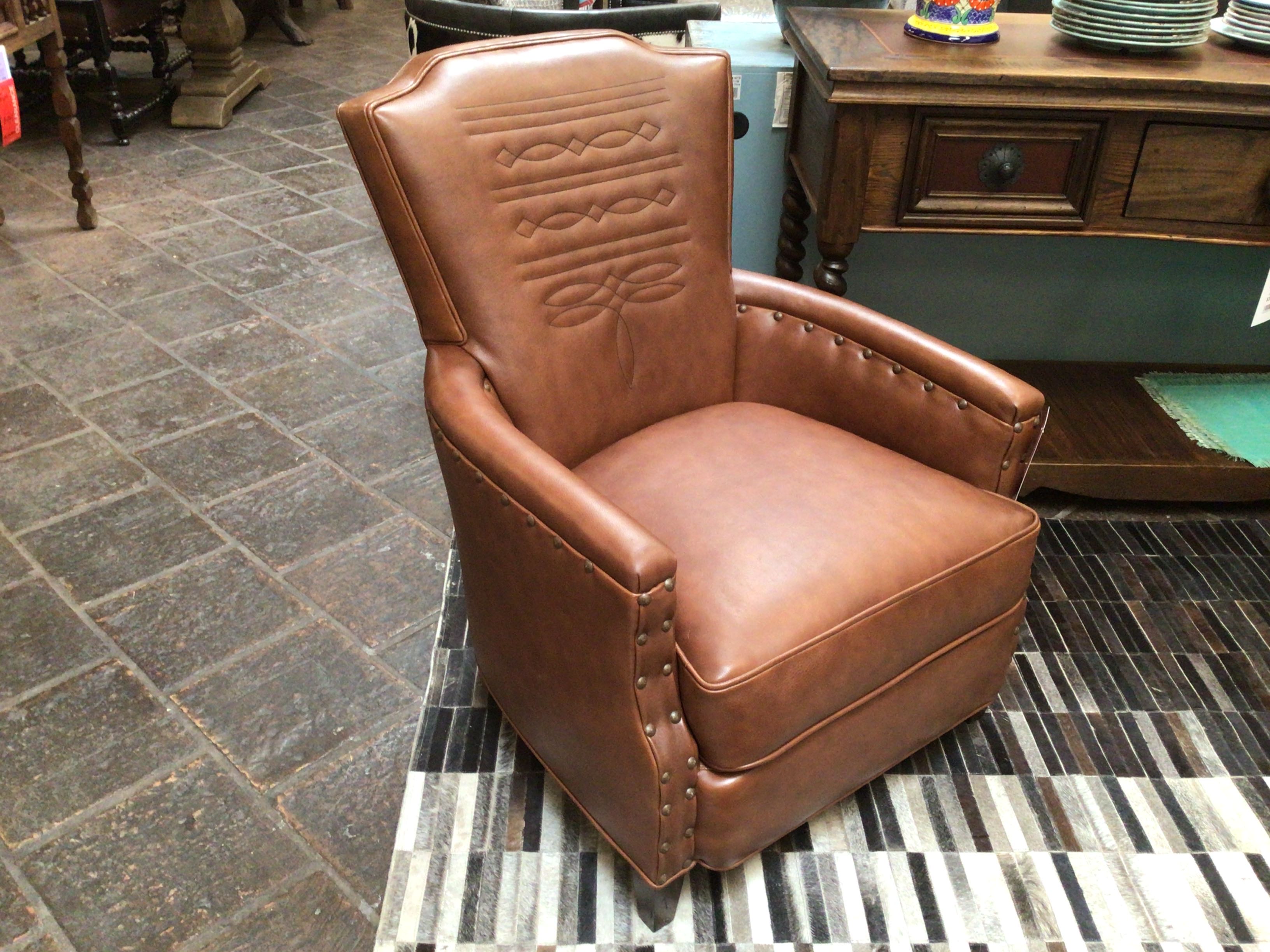 Brown leather armchair on a striped rug with a rustic setting
