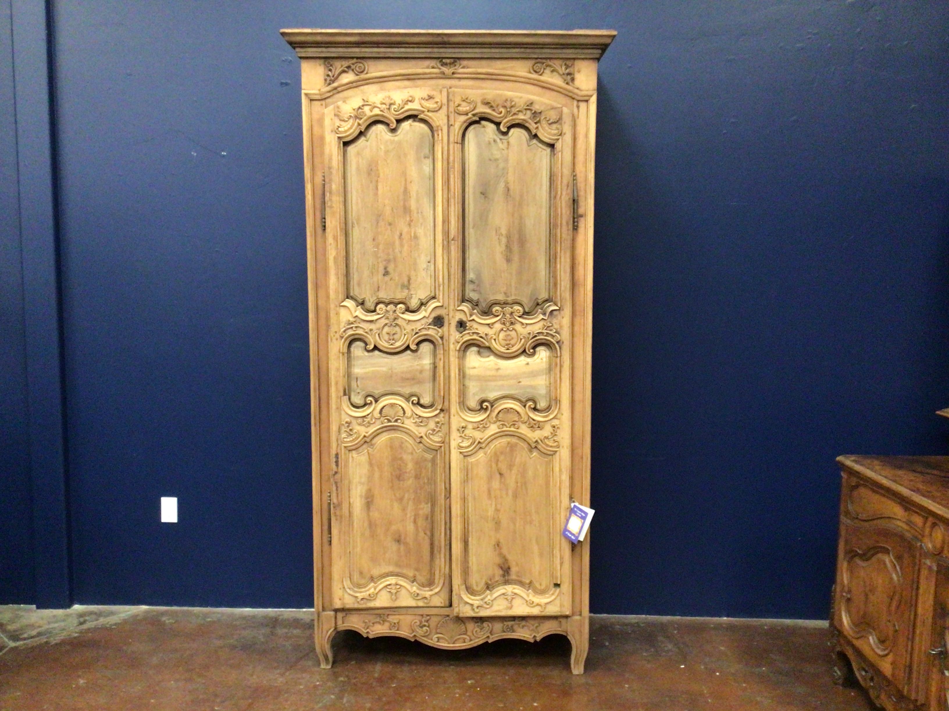 Wooden armoire with intricate carvings against a blue wall