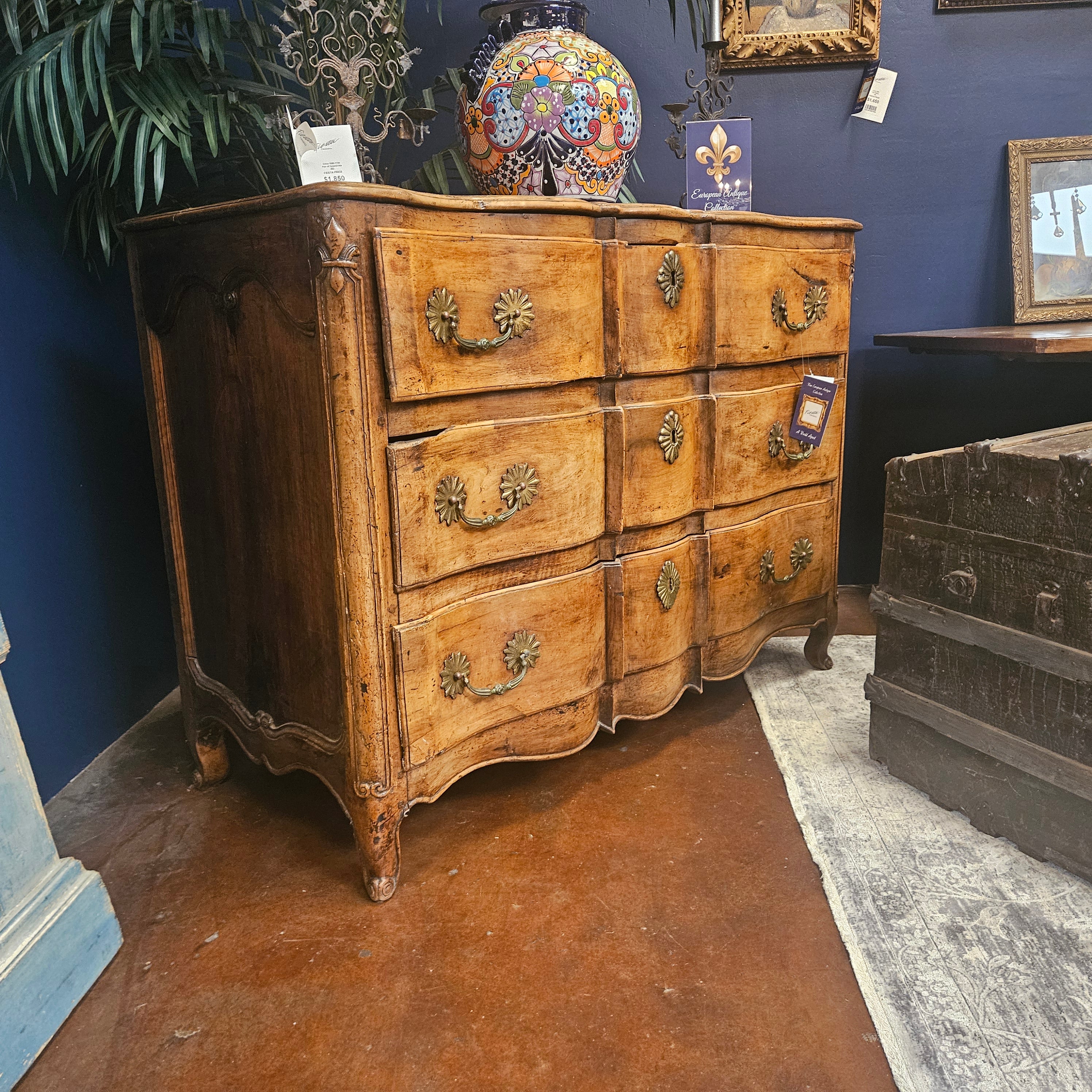 Vintage wooden dresser with decorative elements in a room with blue walls and other furniture.