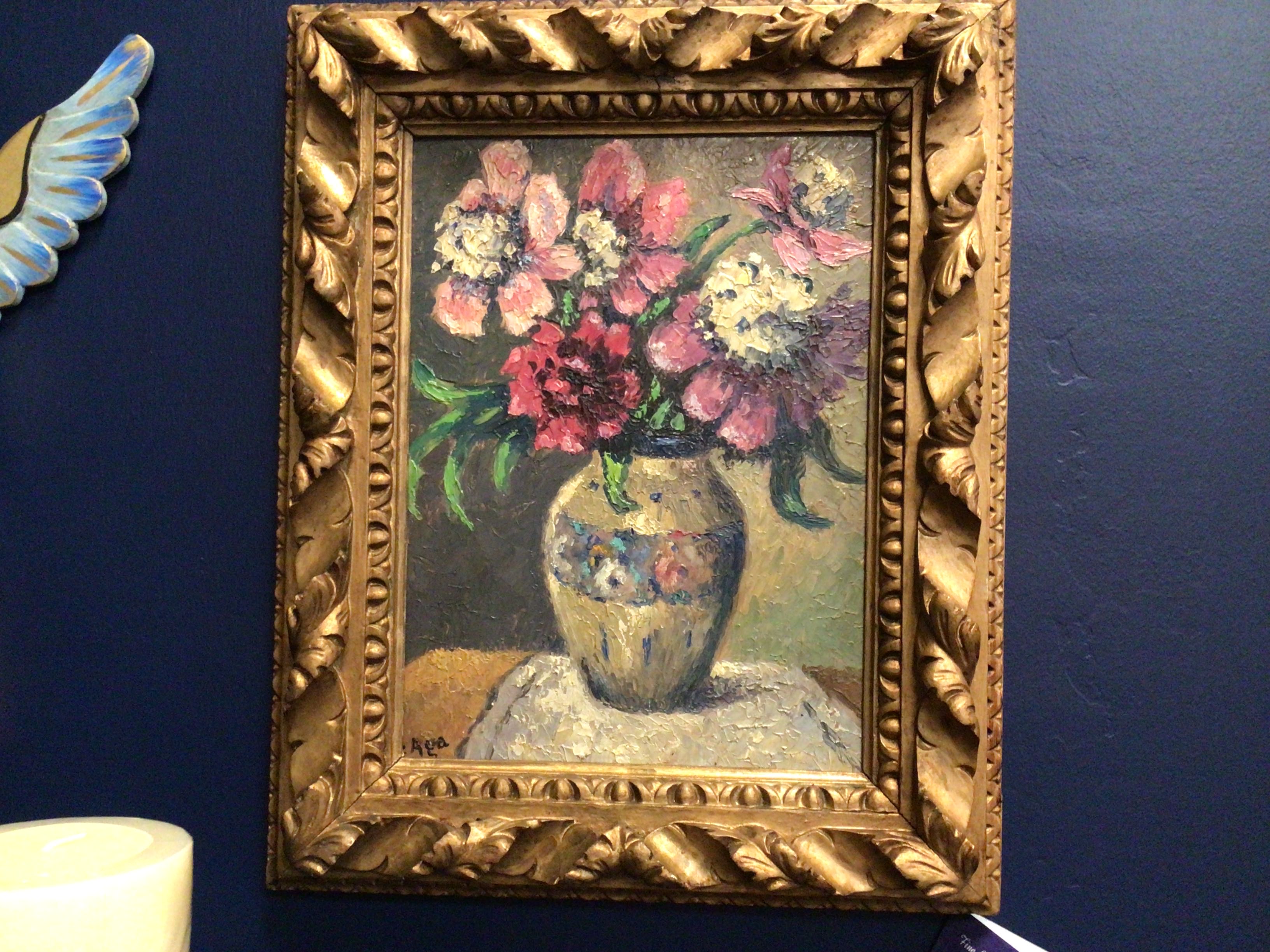 Framed painting of flowers on a blue wall