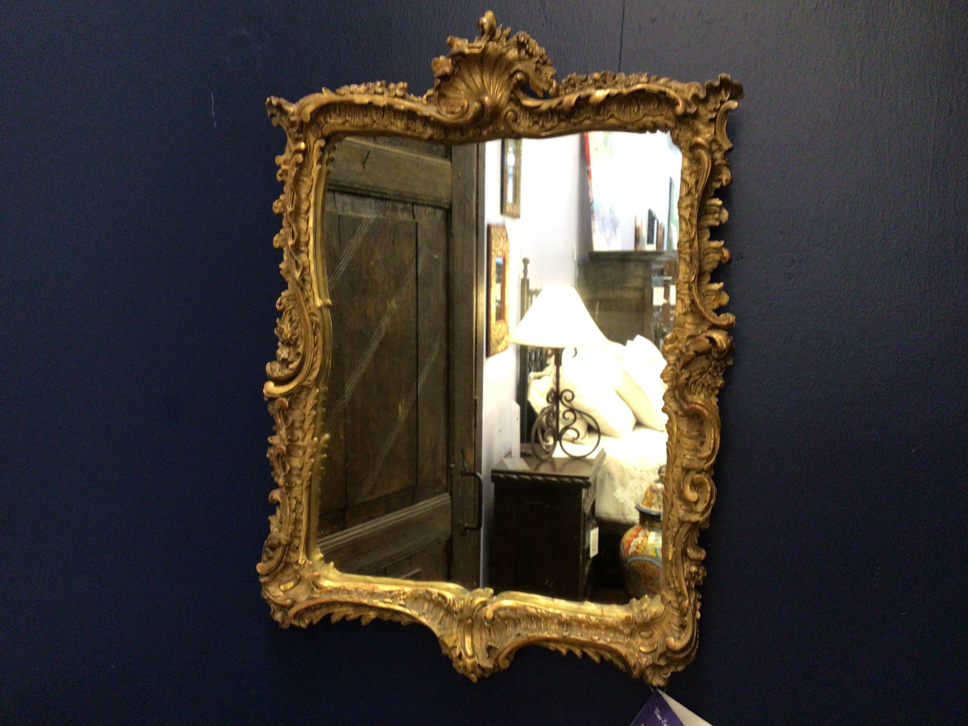 Decorative gold-framed mirror on a dark blue wall