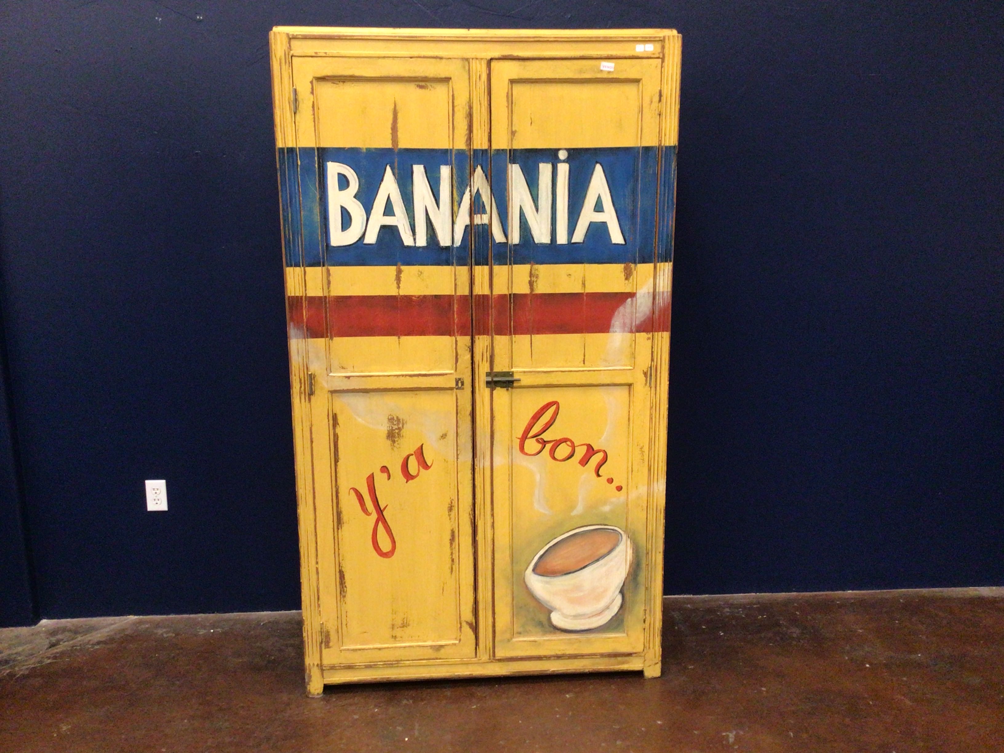 Vintage-style cabinet with 'BANANIA' and 'ya bon' text against a dark blue wall.