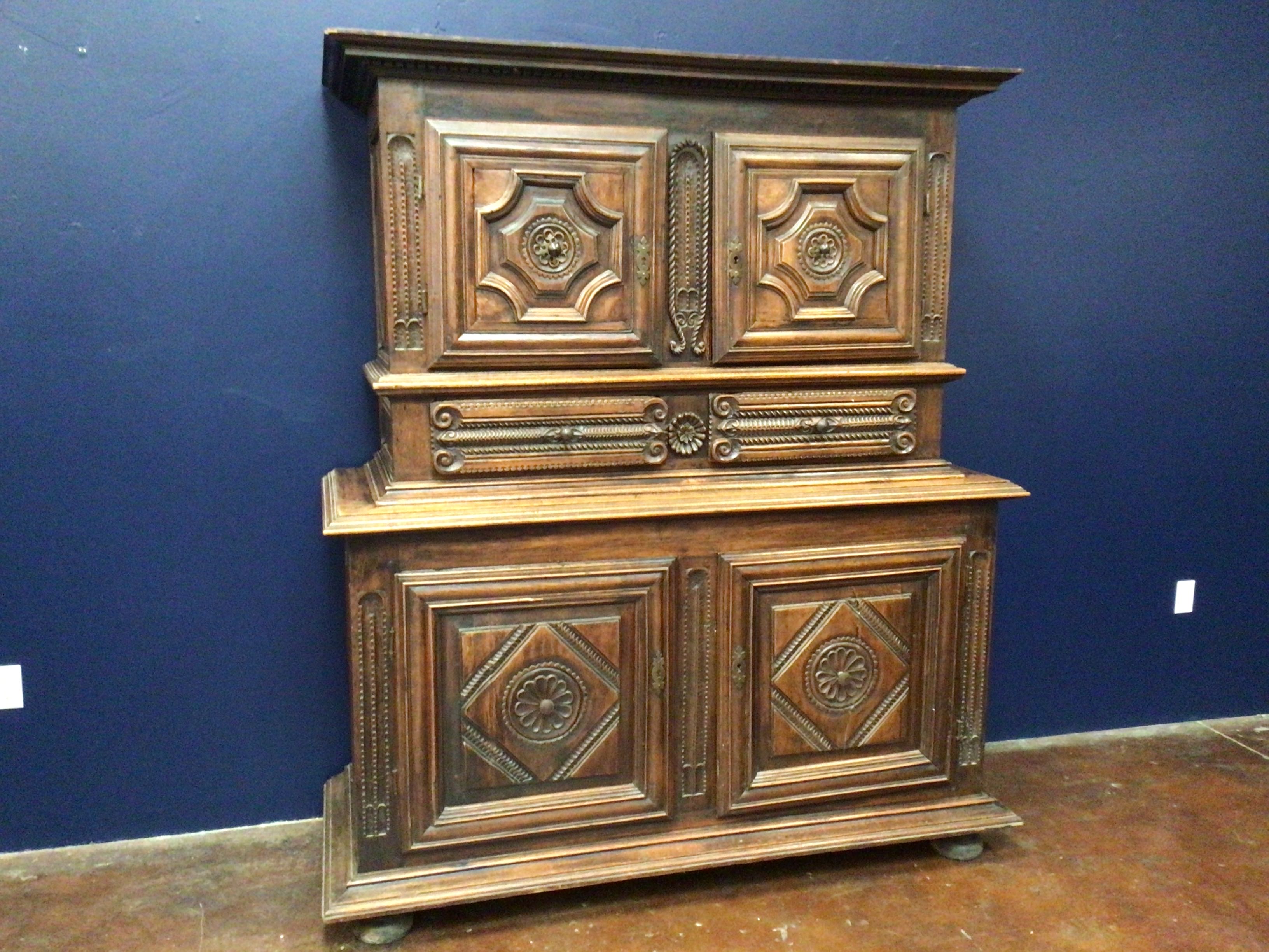 Wooden cabinet with intricate carvings against a blue wall