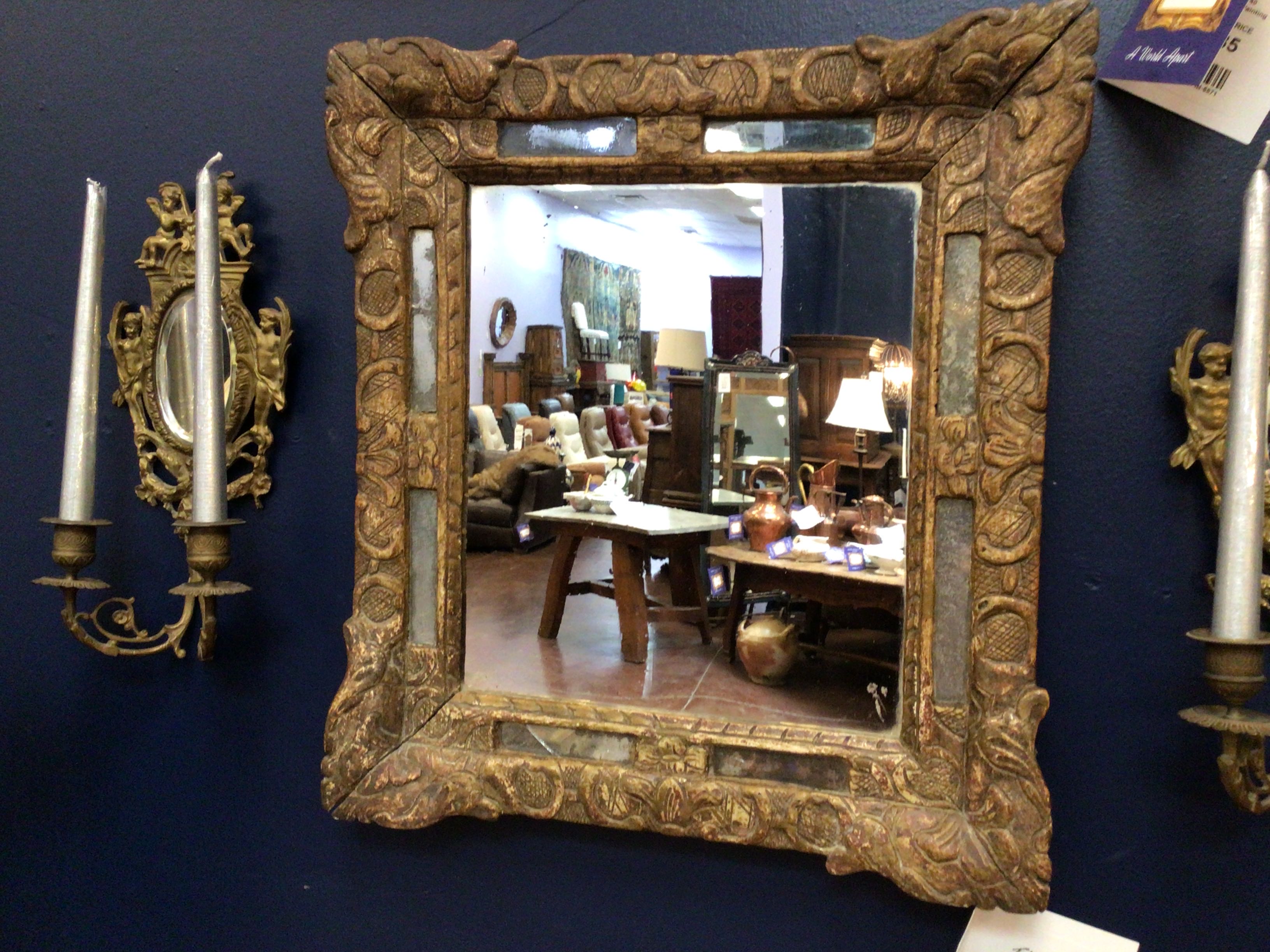 Decorative mirror with intricate gold frame on a dark blue wall
