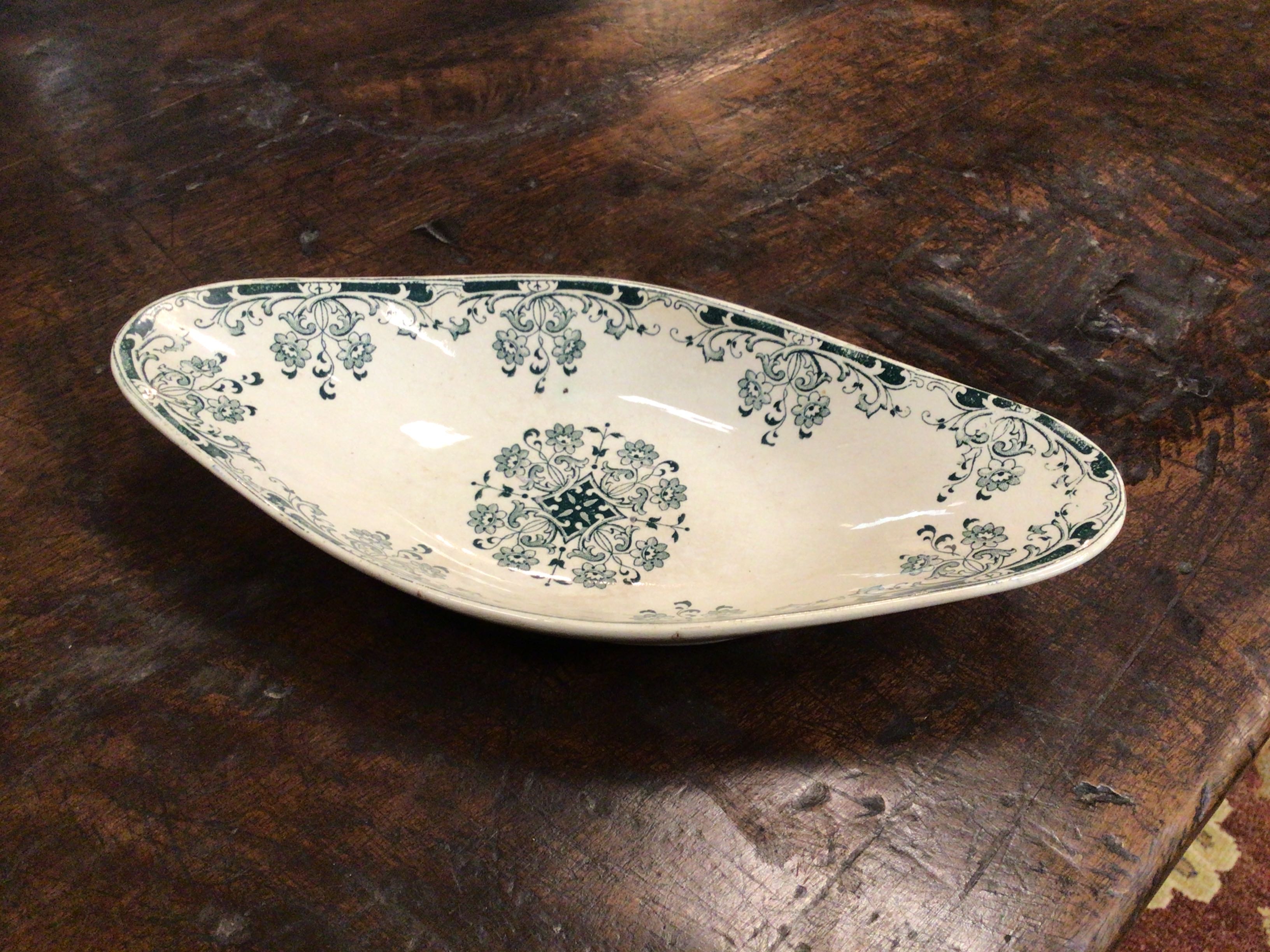 Decorative ceramic platter with green floral patterns on a wooden surface