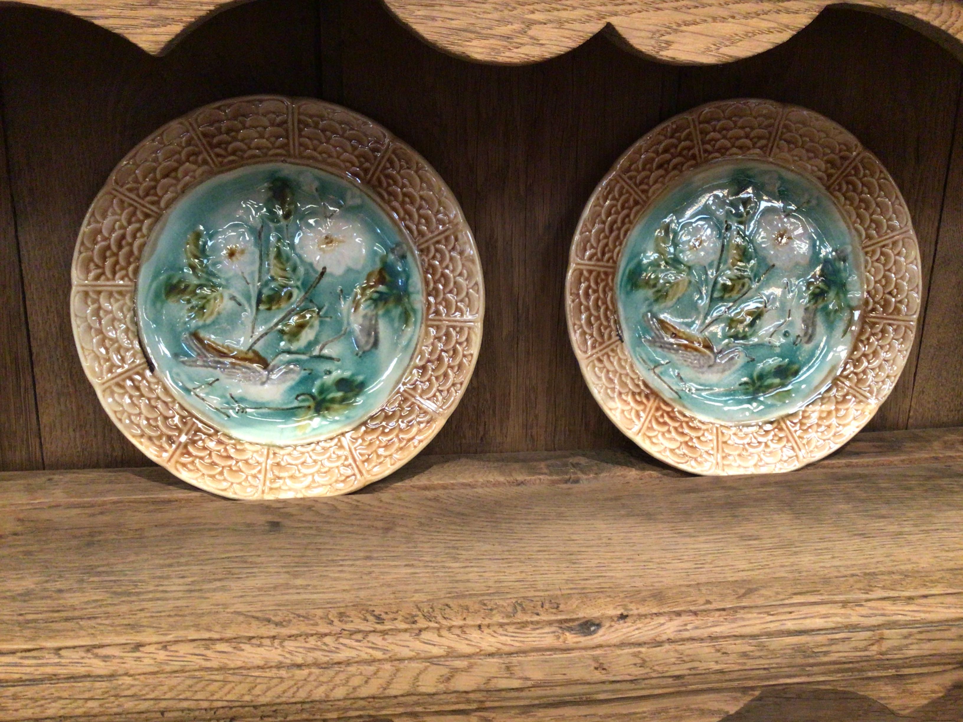 Two ceramic plates with floral designs on a wooden shelf