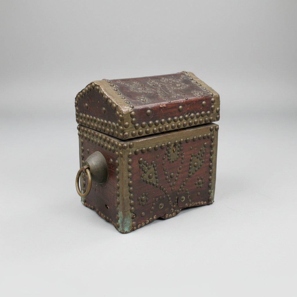 Decorative wooden box with metal studs and a ring on a light gray background