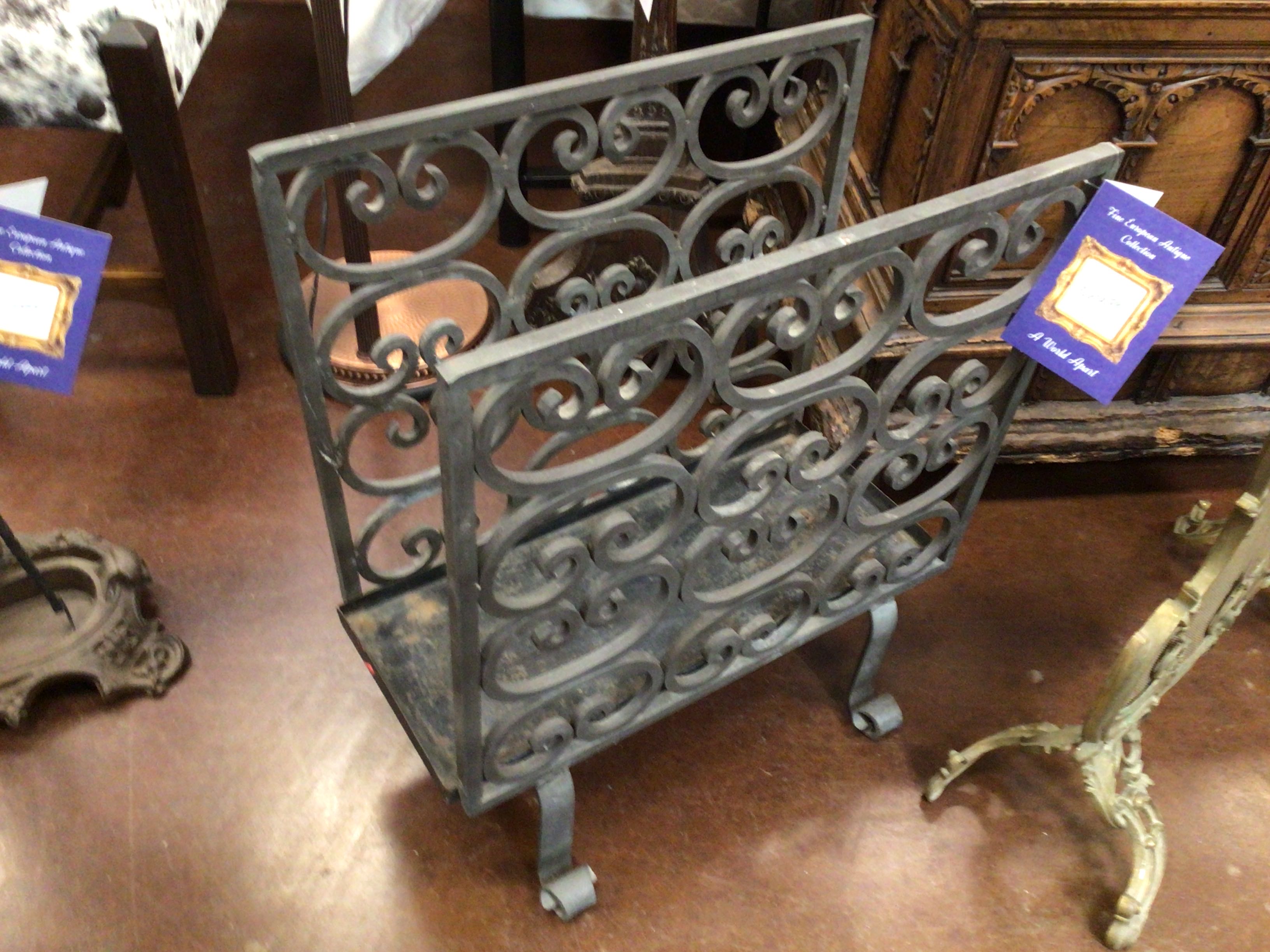 Decorative metal fireback with intricate designs on a brown floor.