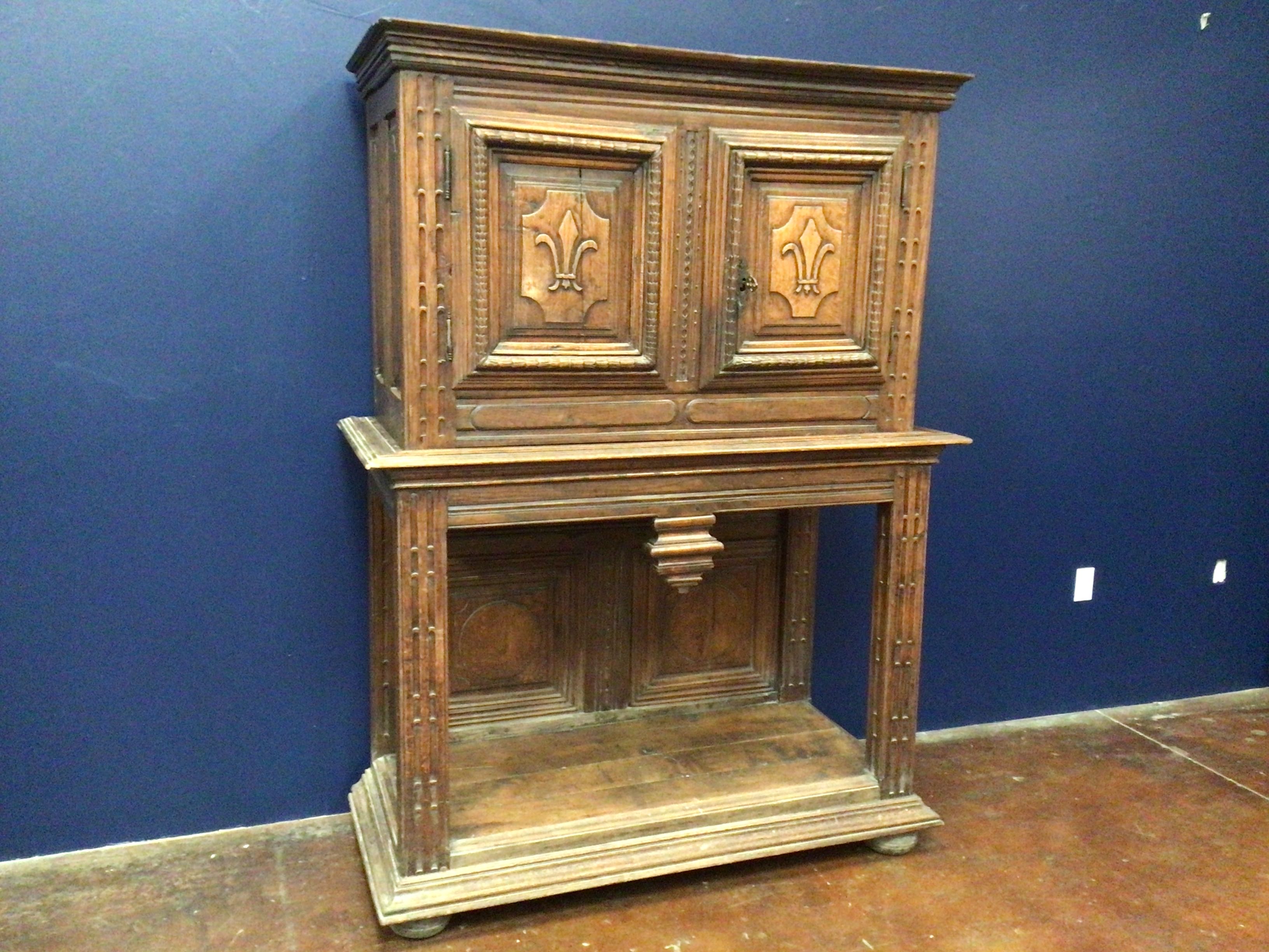 Wooden cabinet with intricate carvings against a blue wall