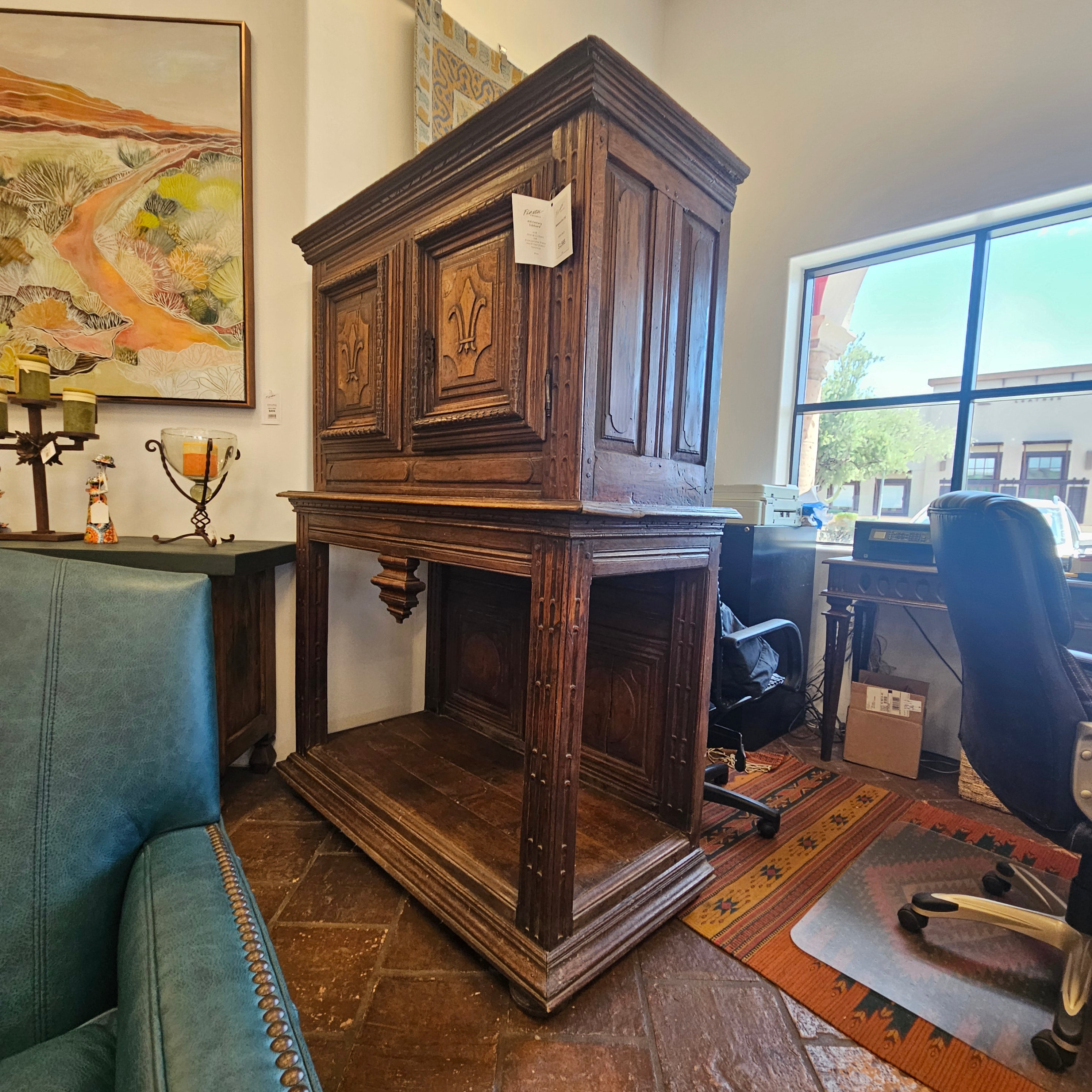 Wooden cabinet with decorative carvings in a room with a couch and artwork.