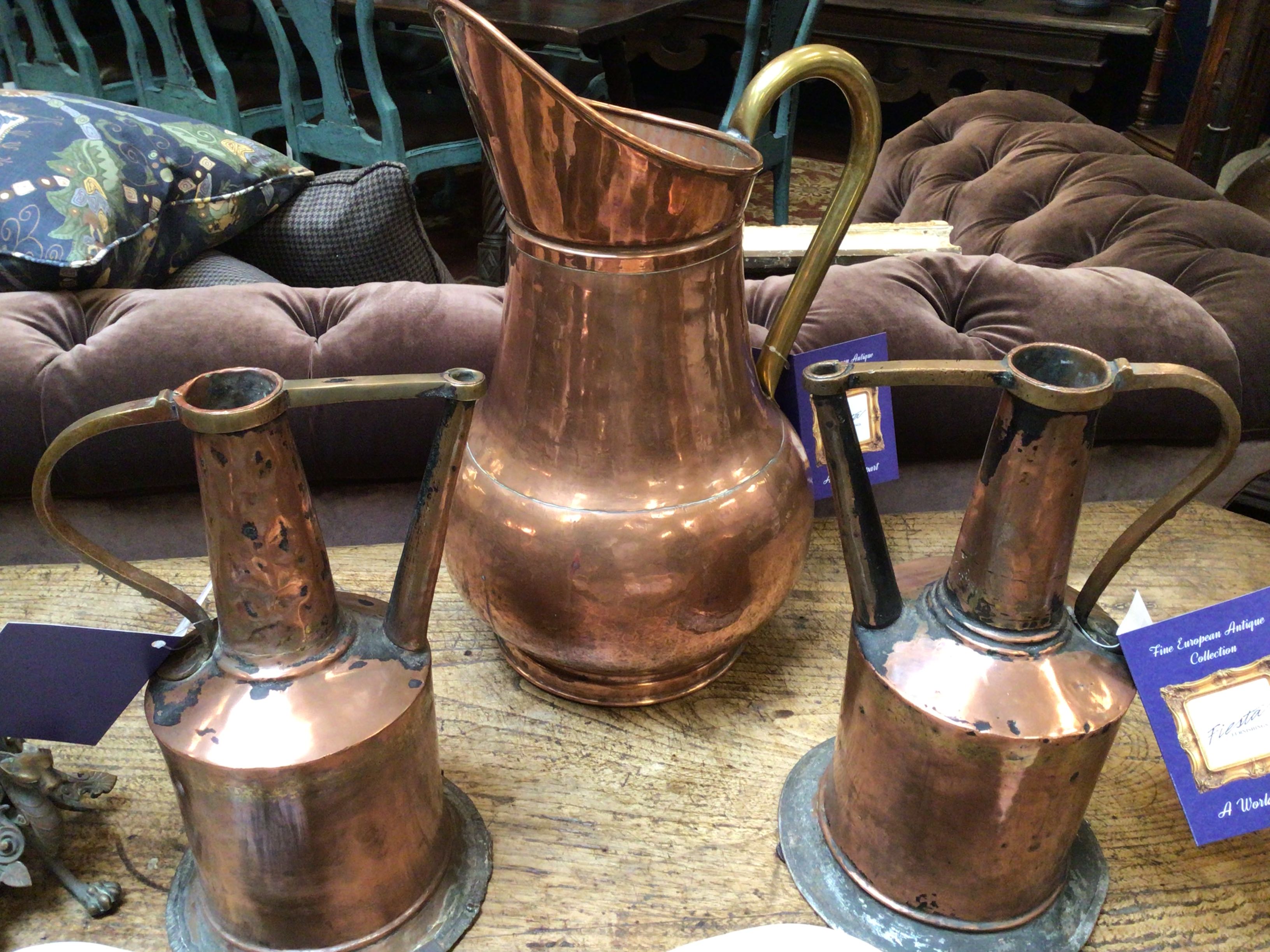 Three copper jugs on a table with a blurred background