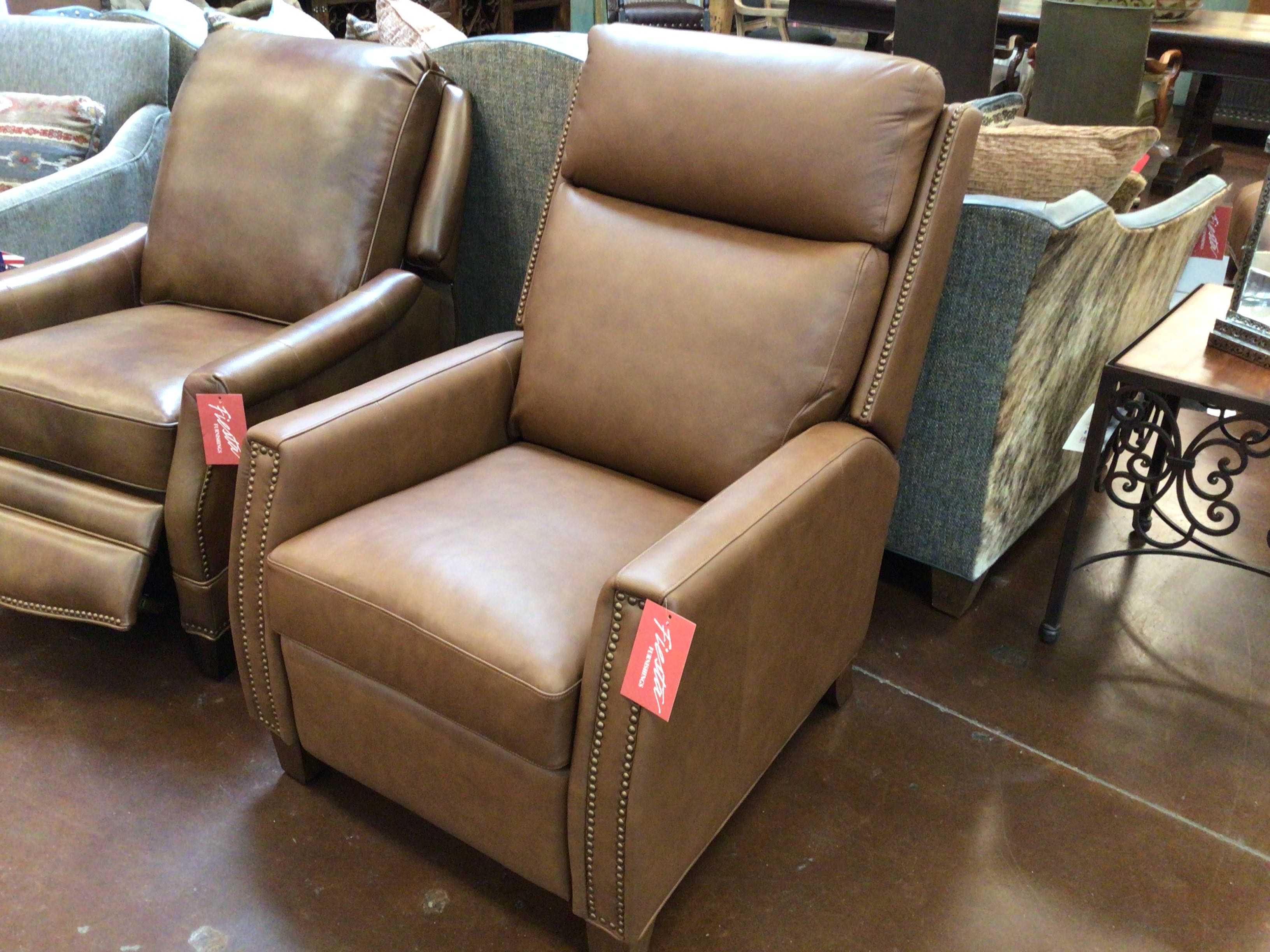Brown leather recliner chairs with price tags in a showroom setting.