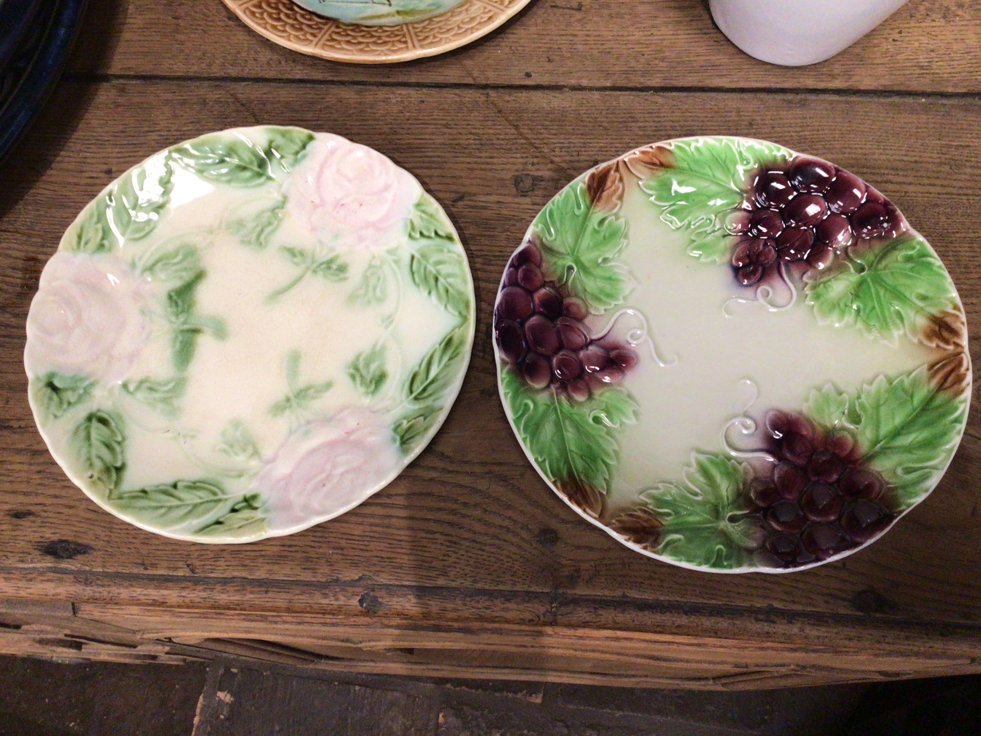 Two ceramic plates with floral and grape designs on a wooden surface