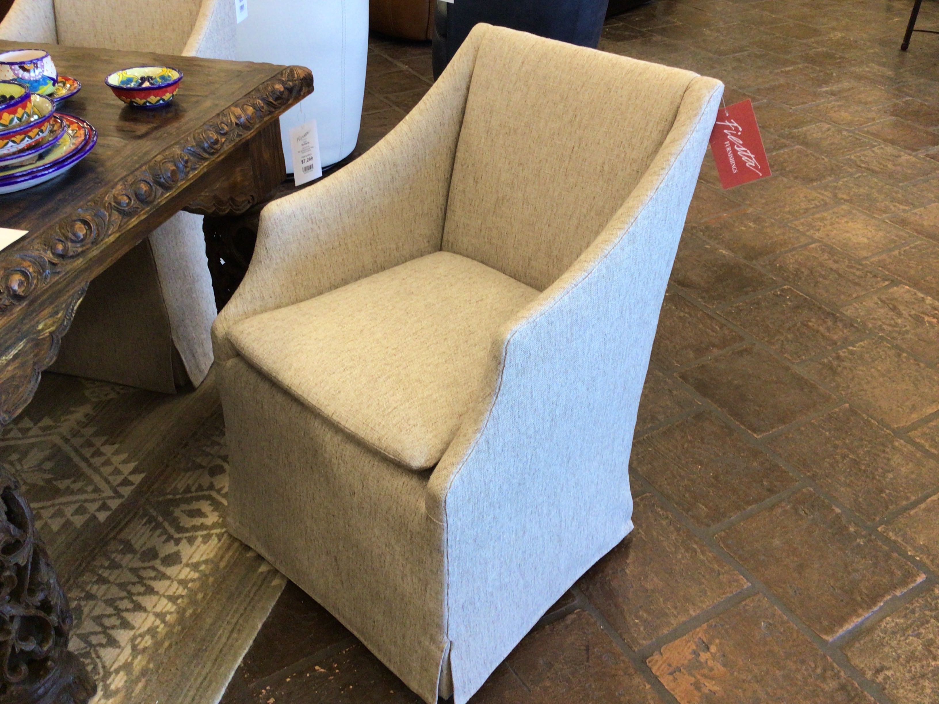 Beige armchair in a store setting with a wooden table and various items in the background.