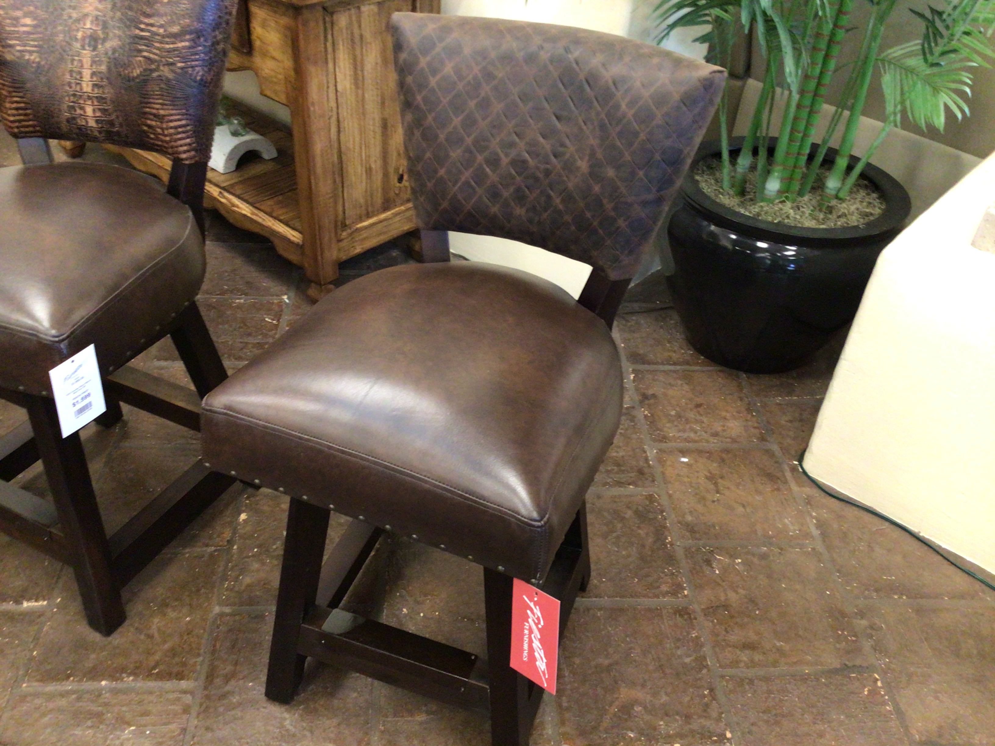 Brown leather bar stools with quilted backrests on a stone floor.