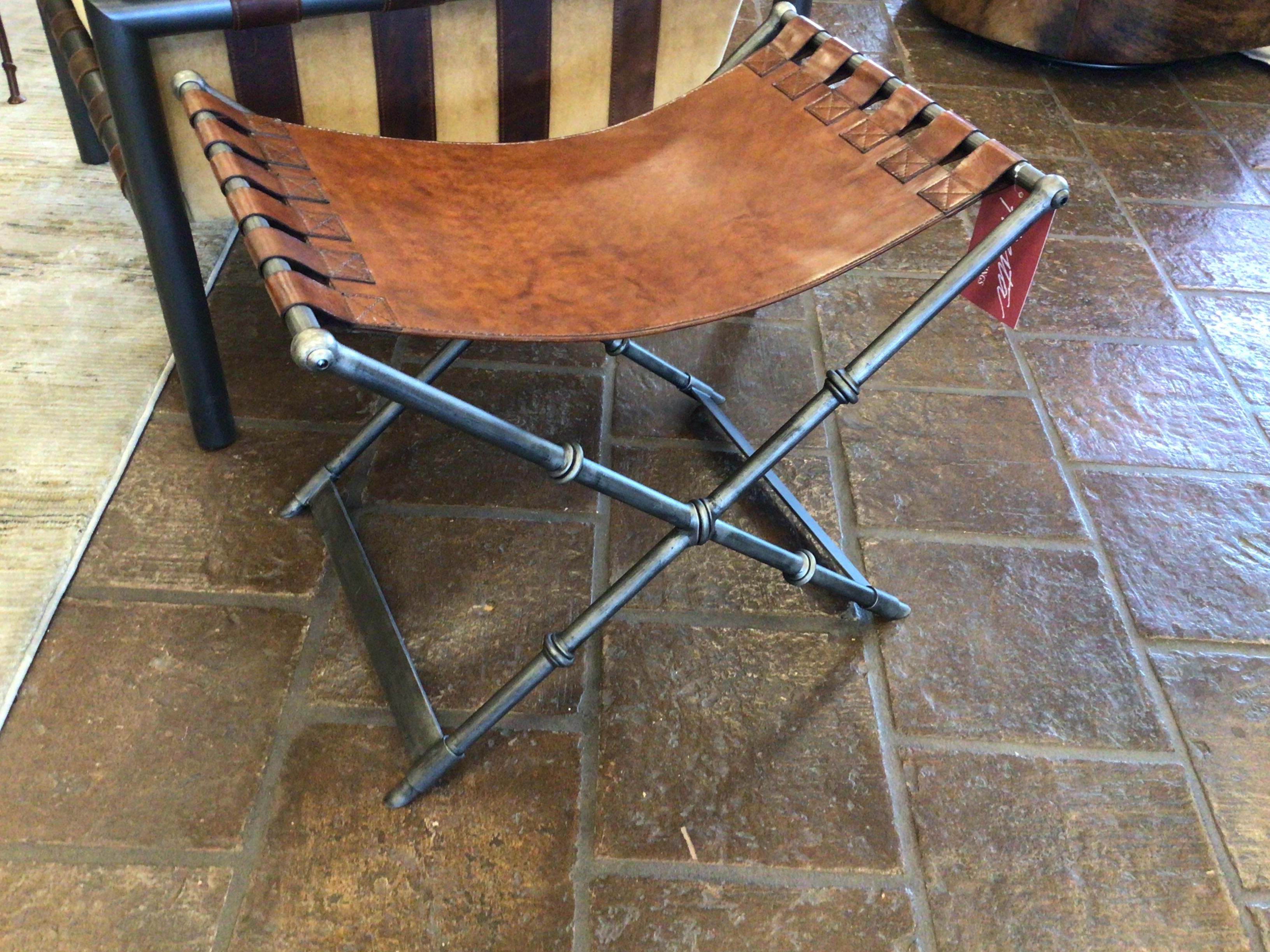 Brown leather stool with metal legs on a tiled floor