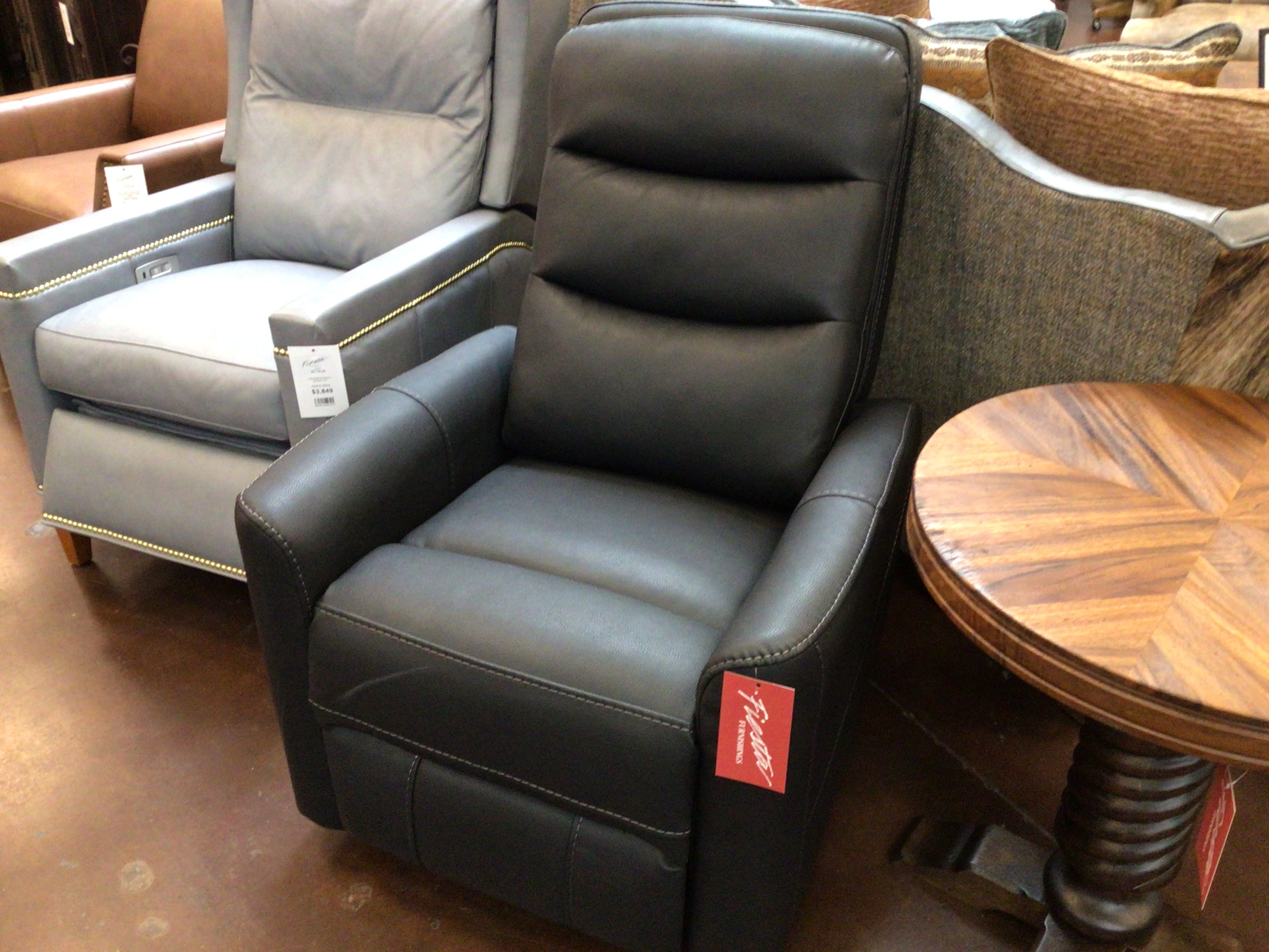 Black recliner chair with a visible brand tag in a furniture store setting.