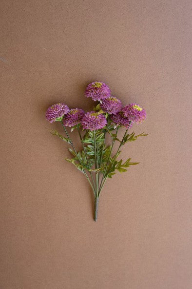 Bouquet of purple flowers with green leaves on a brown background