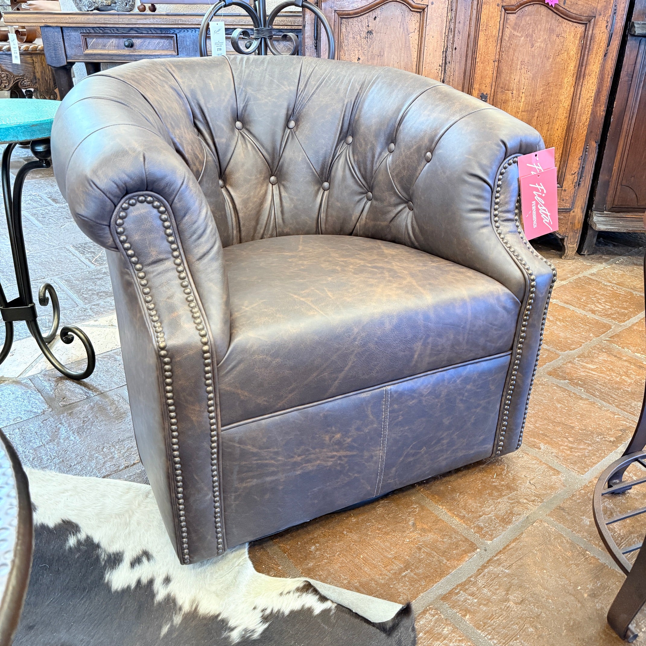 Brown tufted armchair on a tiled floor with a wooden cabinet in the background