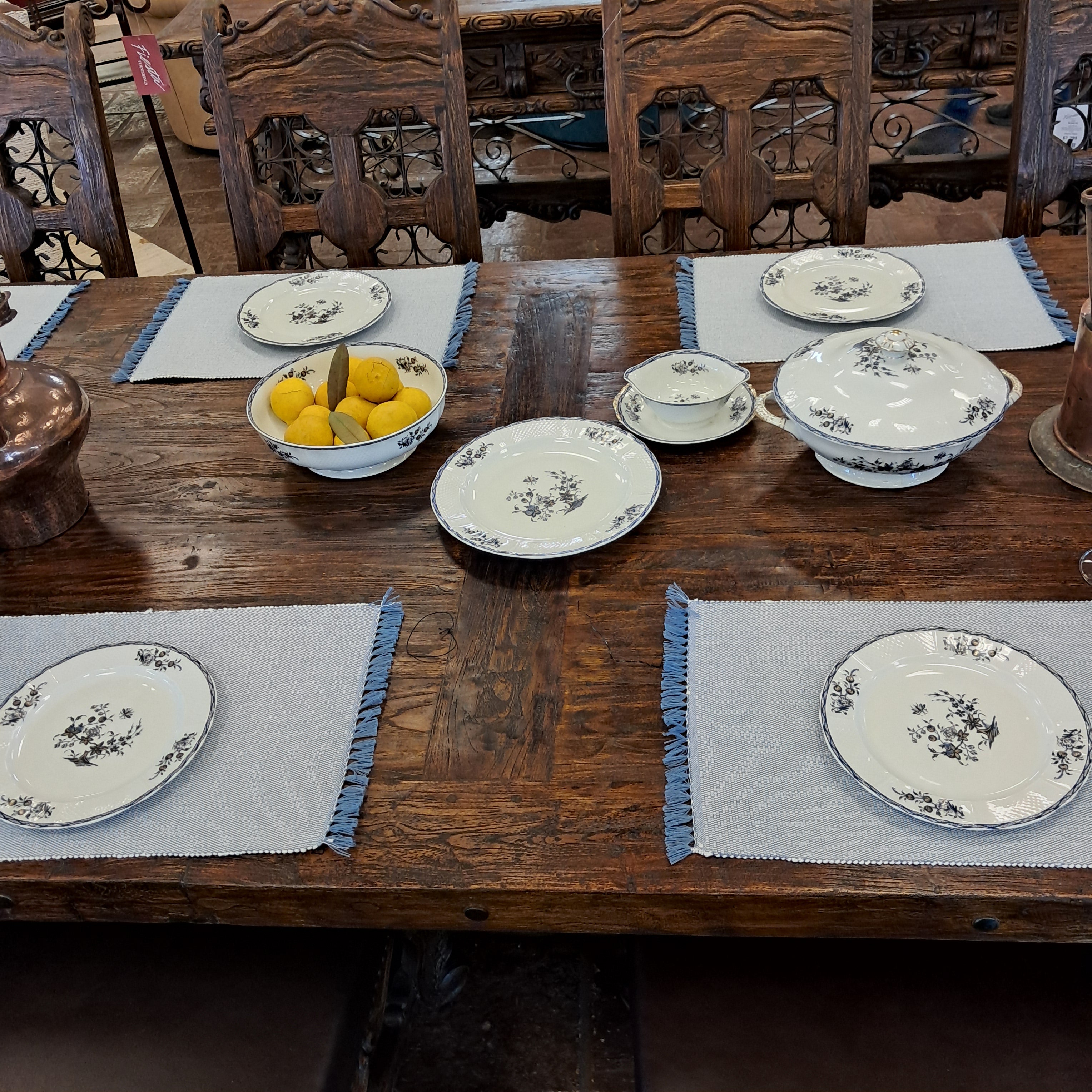 Decorative plates with floral patterns on a wooden table with gray placemats.