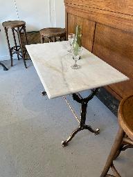 Three bistro tables with white marble tops on cast iron pedestal bases