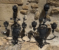 Pair of wrought iron Gothic wall sconces with figural detail and multiple candle arms