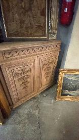 French carved corner cabinet in warm honey oak with panel doors and a carved frieze