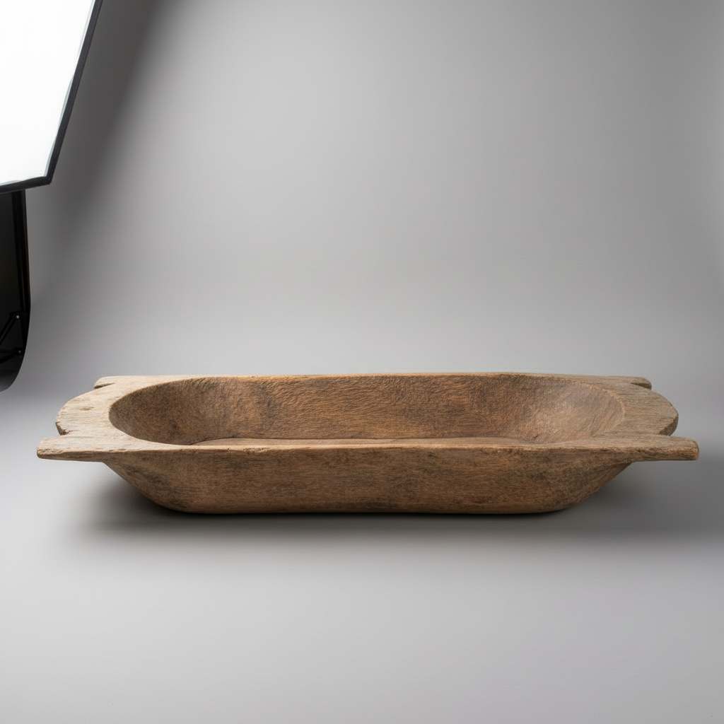 A rustic, hand-carved wooden tray with a deep oval center and wide, slightly uneven flared sides, shown on a neutral gray studio background.
