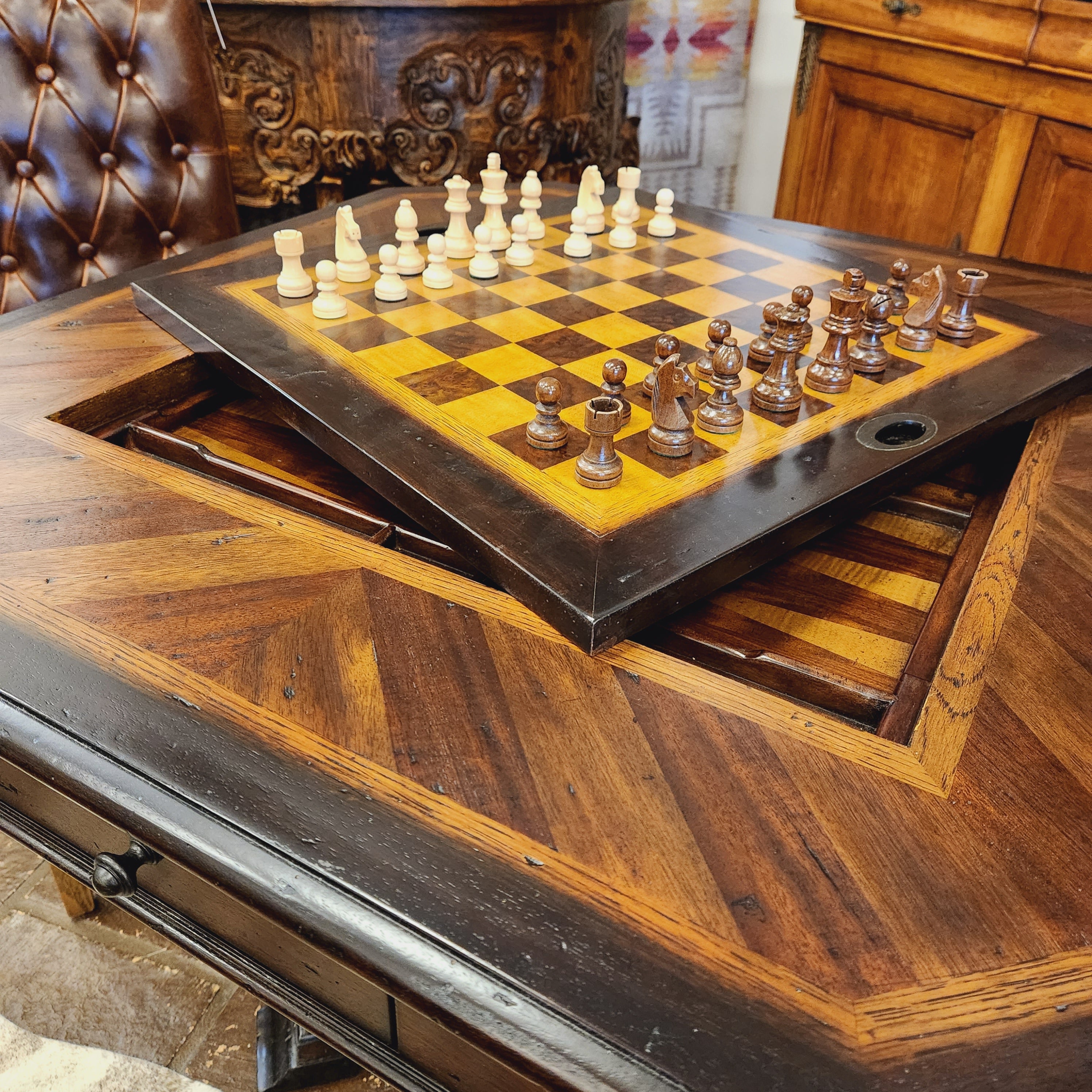 Wooden chessboard with chess pieces inside a wooden cabinet.