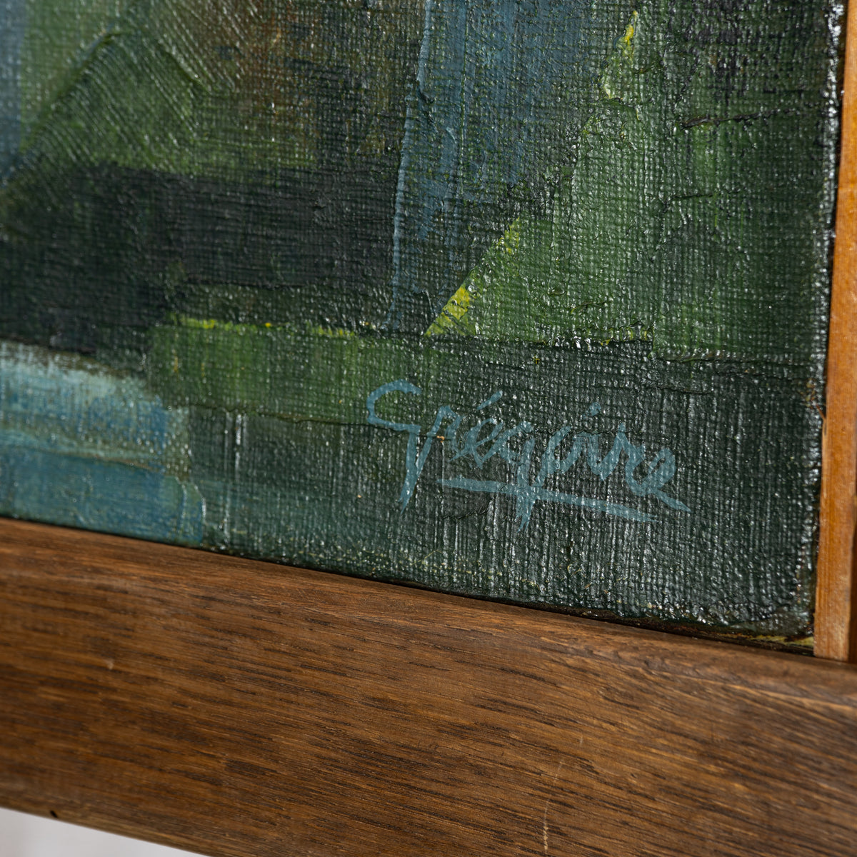 Close-up of a framed painting showing textured dark green and blue brushstrokes, a light blue artist signature reading 'Gaspard', and a warm brown wooden frame.
