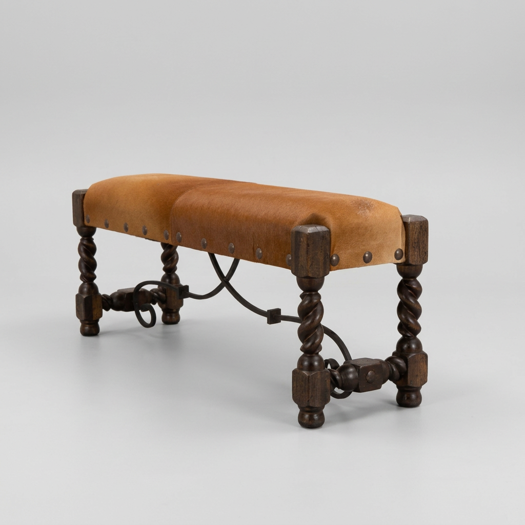 A rustic wooden bench with a tan cowhide upholstered seat, dark carved legs, and metal hardware, set against a neutral draped curtain backdrop.