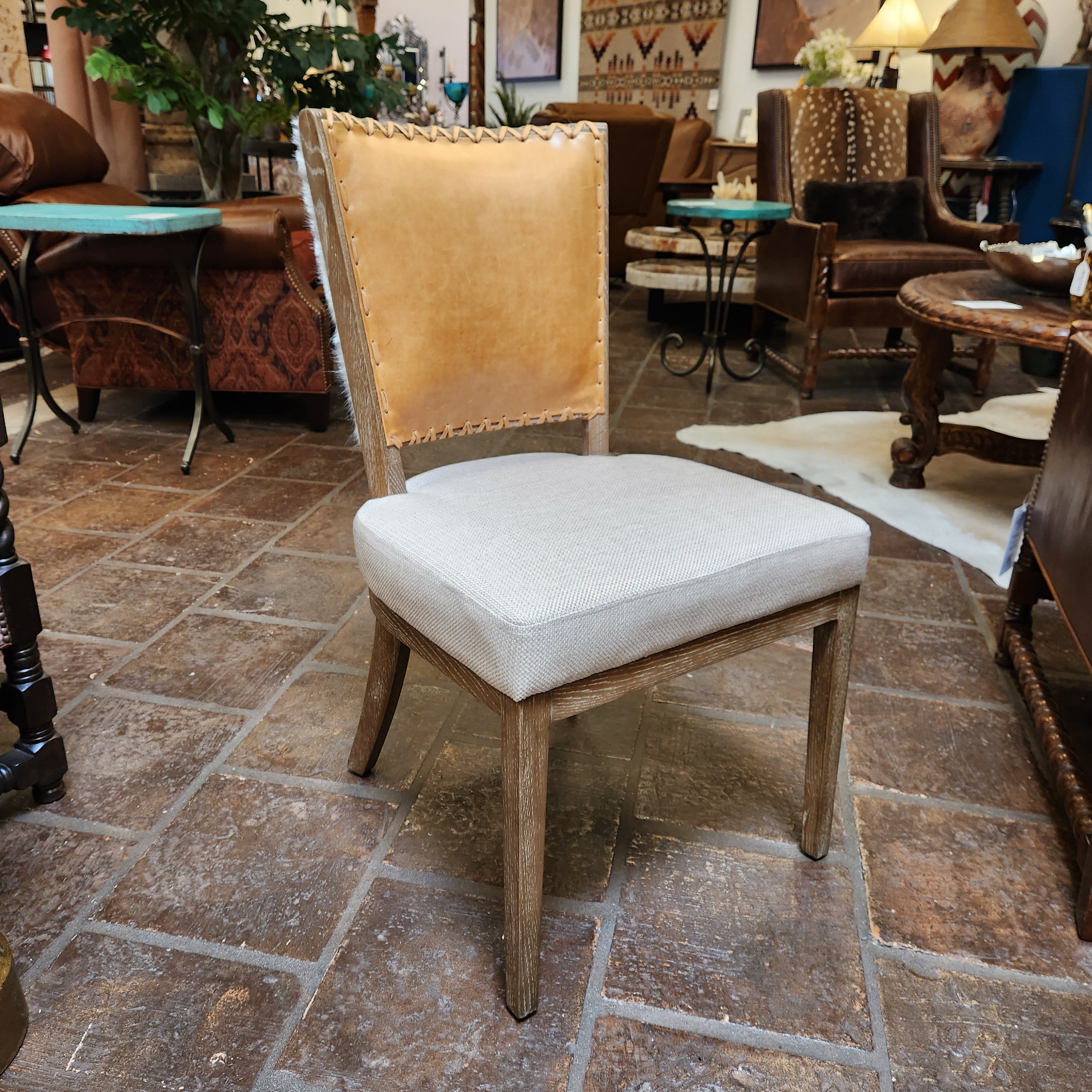 White chair with wooden armrests against a stone wall.