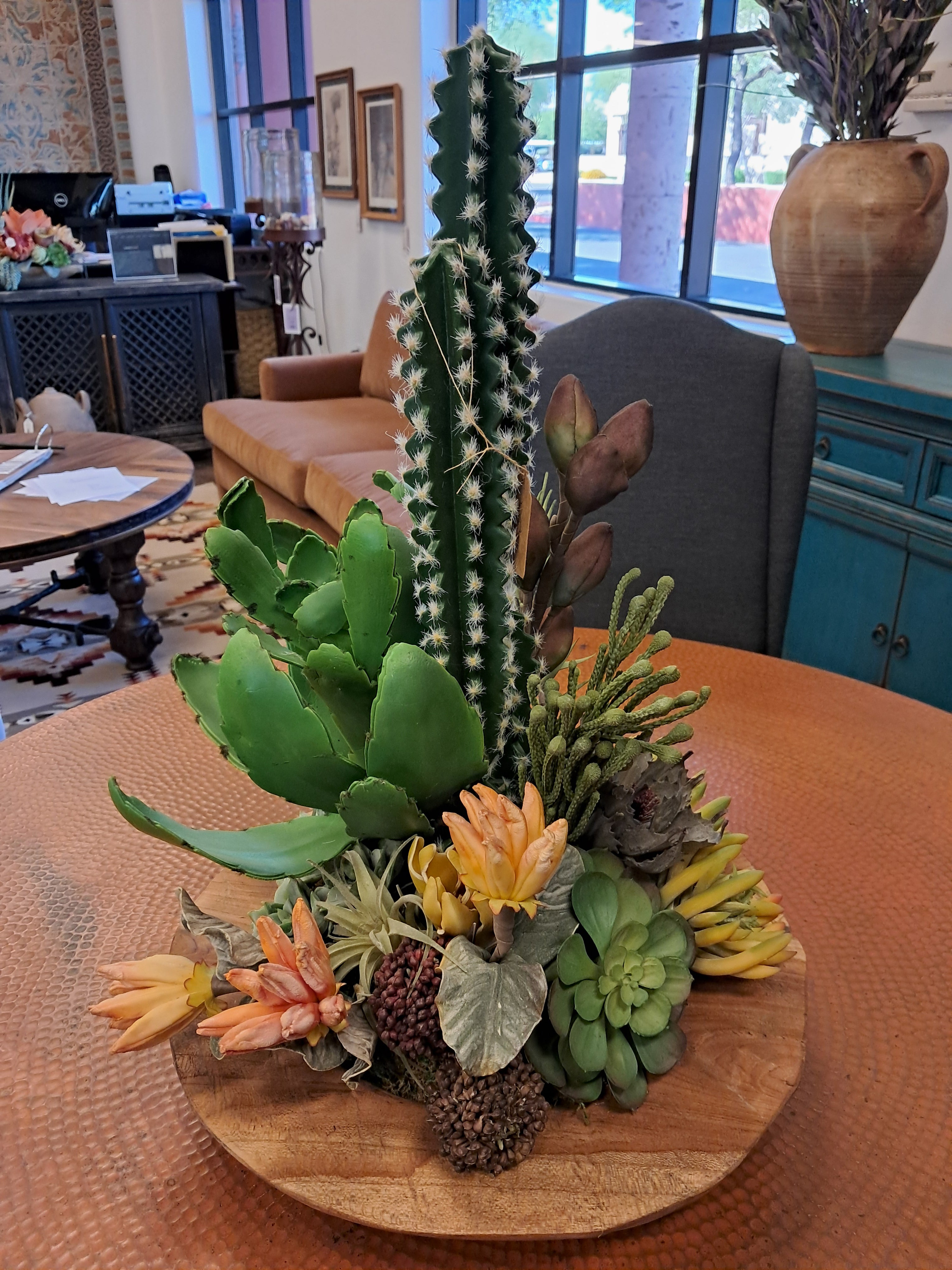 Decorative arrangement of cacti and succulents on a wooden table in an indoor setting.