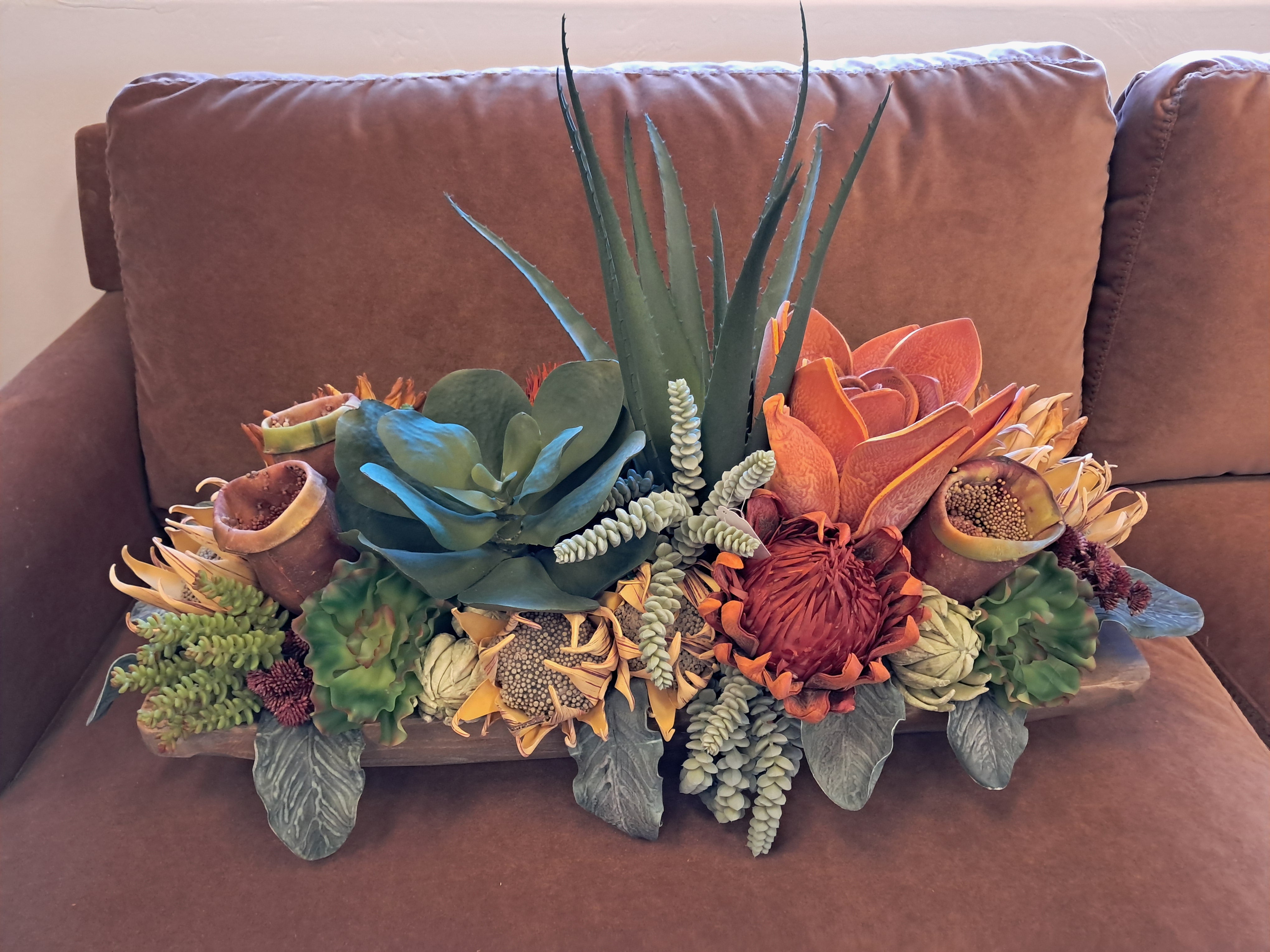 Artificial succulent and floral arrangement on a brown couch
