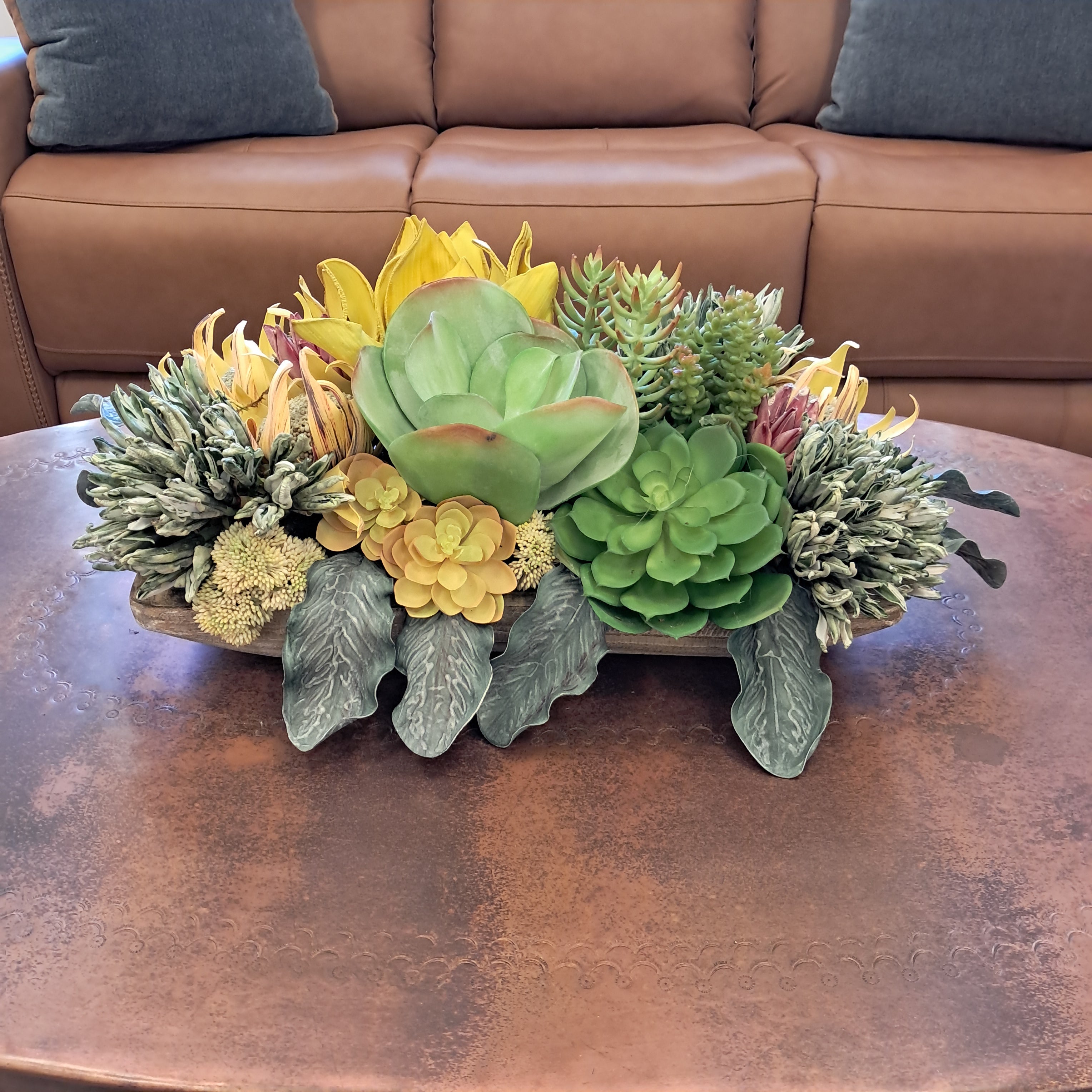Decorative wall piece with succulents and greenery on a brown leather surface