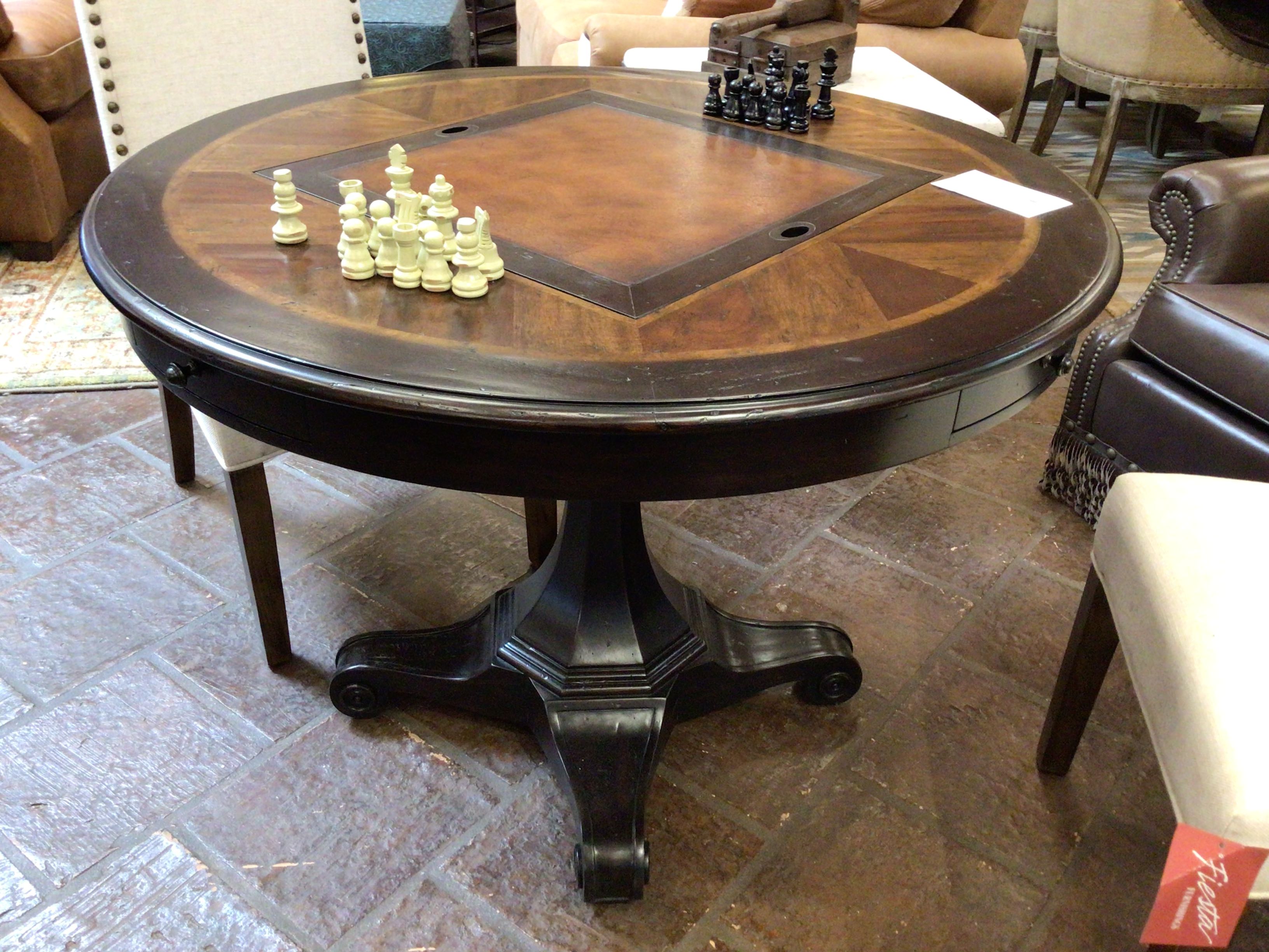 Round wooden table with chess pieces on a stone floor