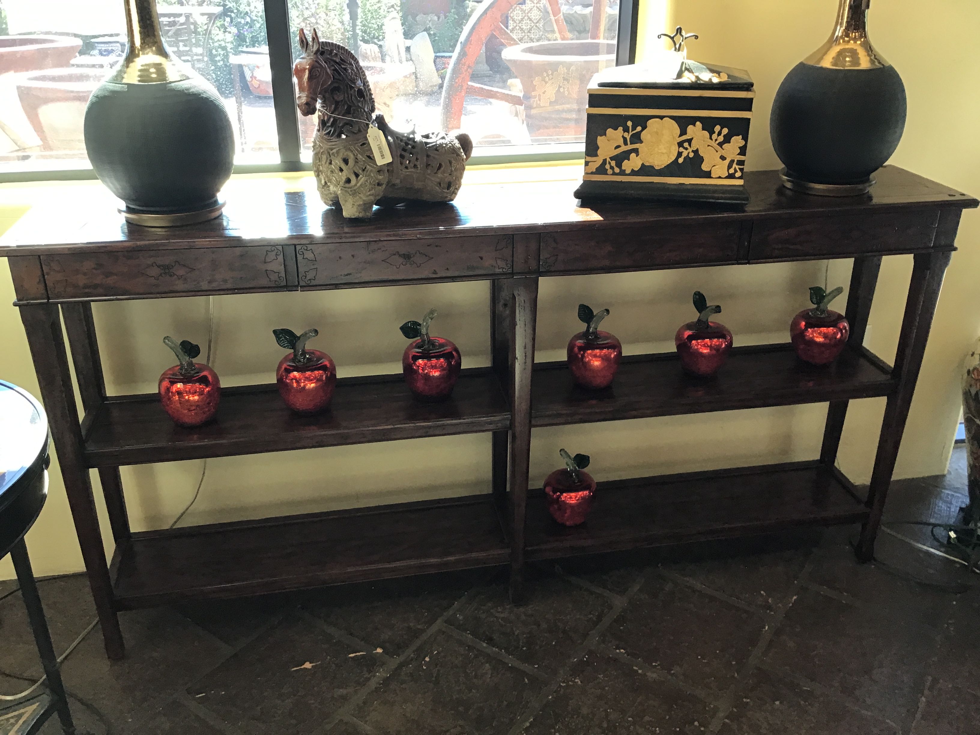 Wooden console table with decorative items including a horse statue, vases, and small red apple-shaped lights.