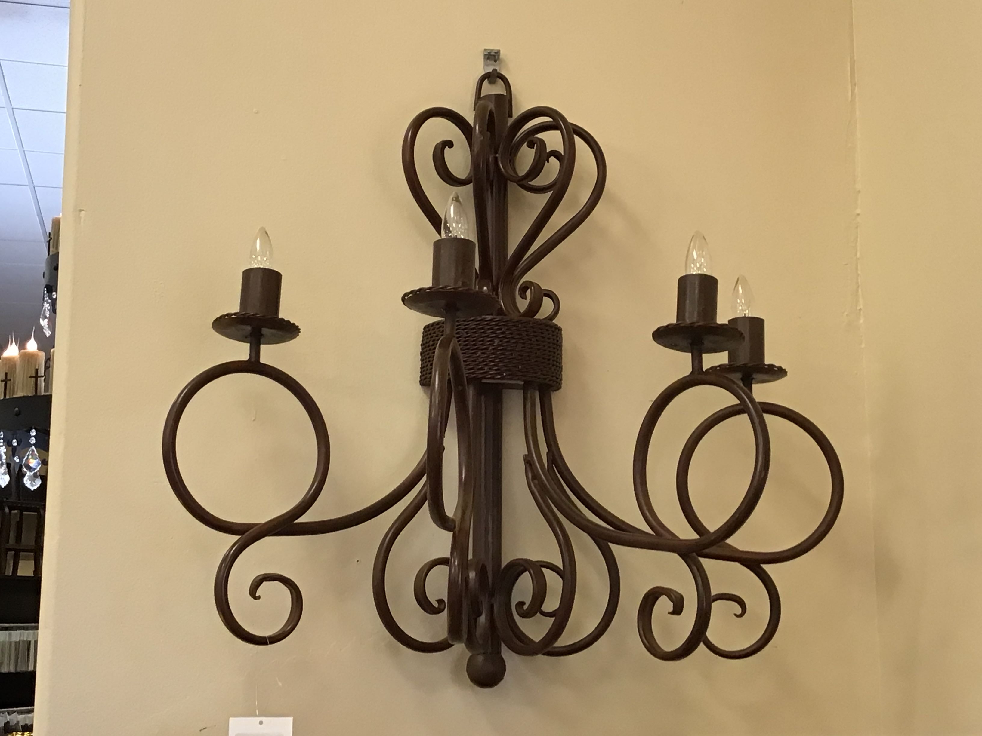 Decorative wall sconce with multiple candle-like lights on a beige wall.
