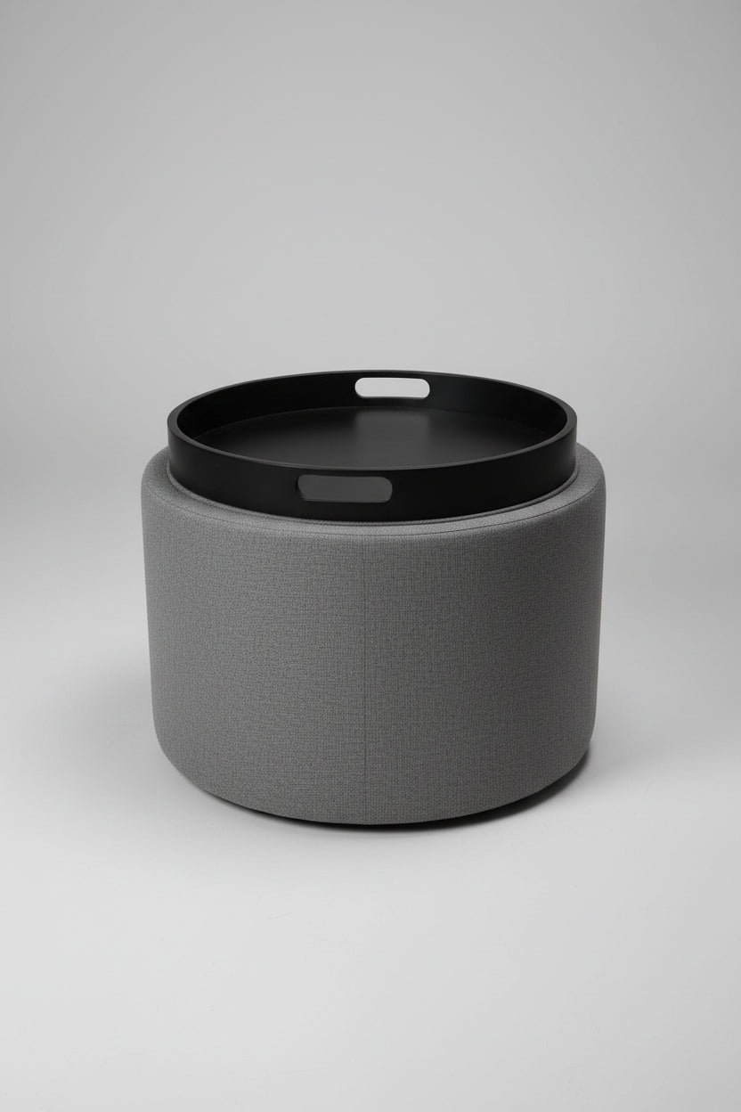 Gray ottoman with a black tray on top containing papers and a pen.
